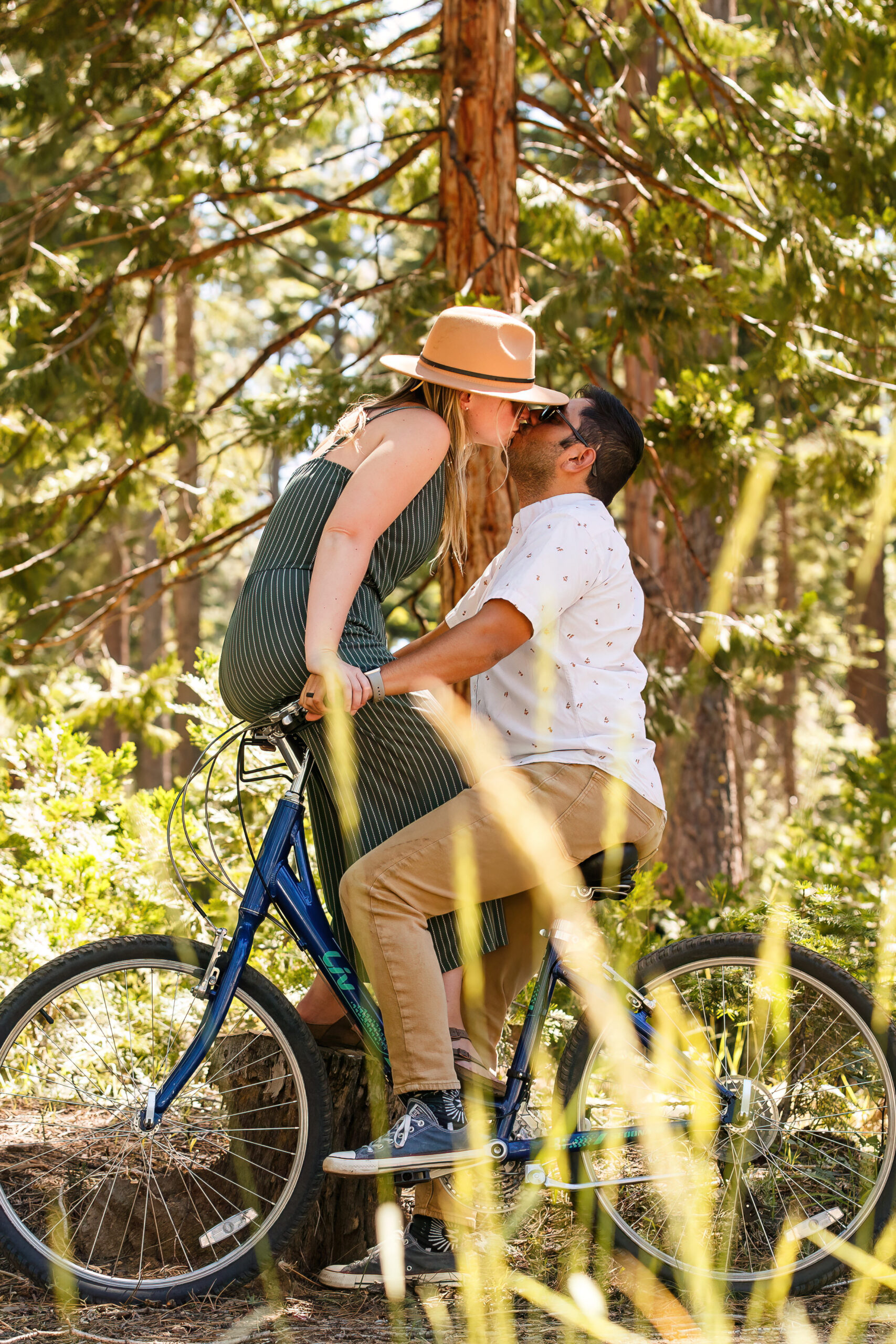 a woman kissing a man as she sits backwards on a bike's handlebars