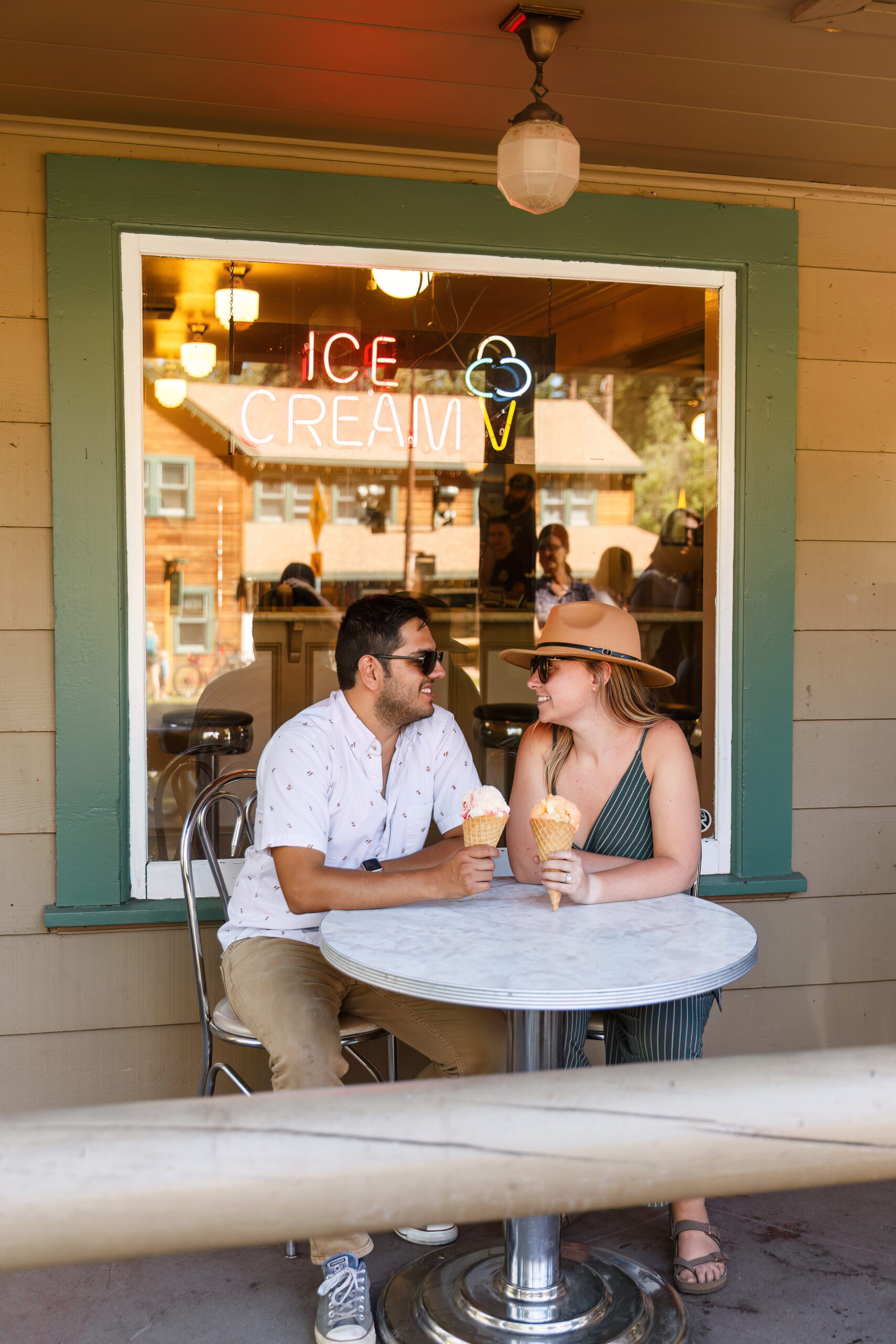 a couple sitting outside an ice cream parlor enjoying a treat