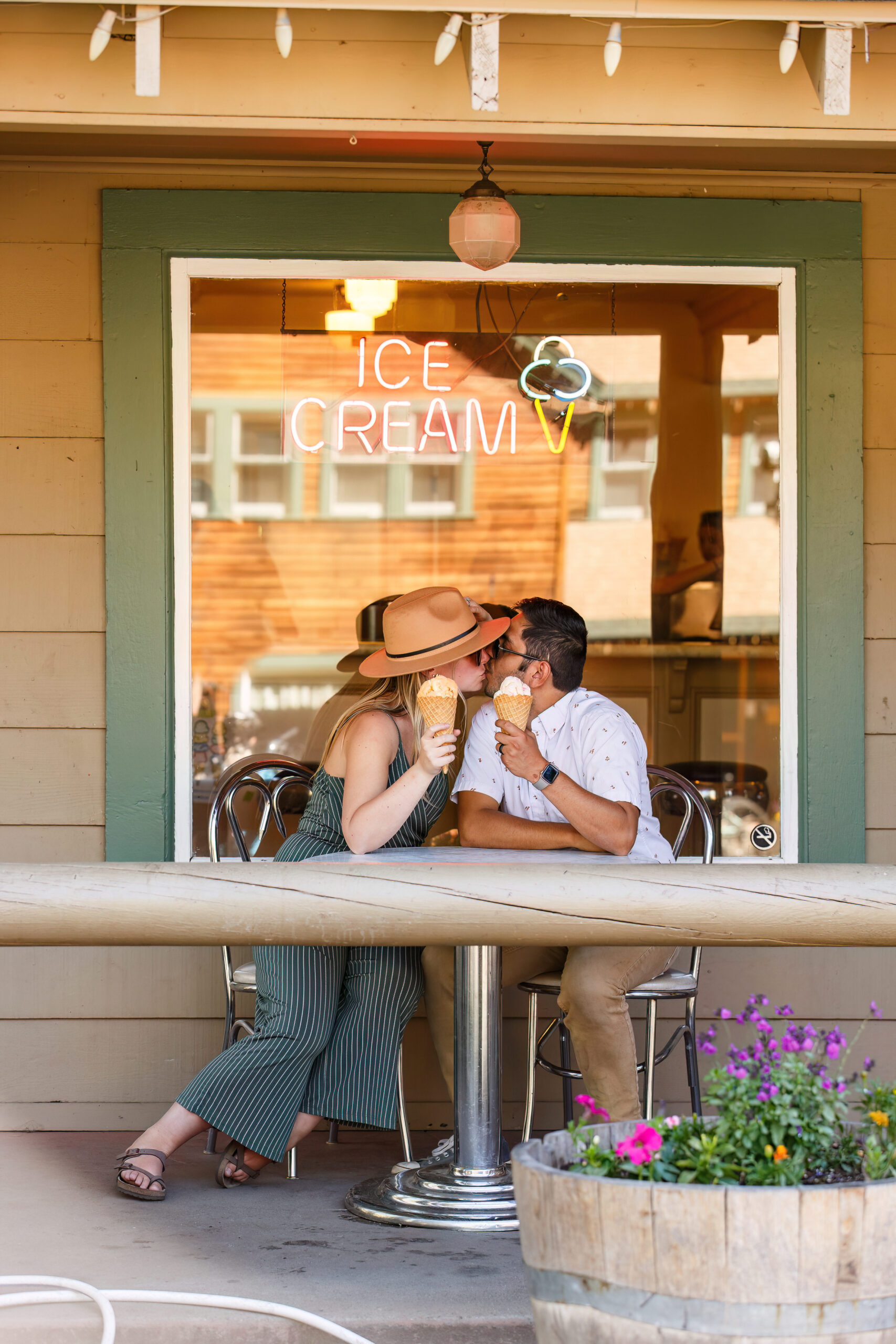 a couple kissing as they sit and eat ice cream together