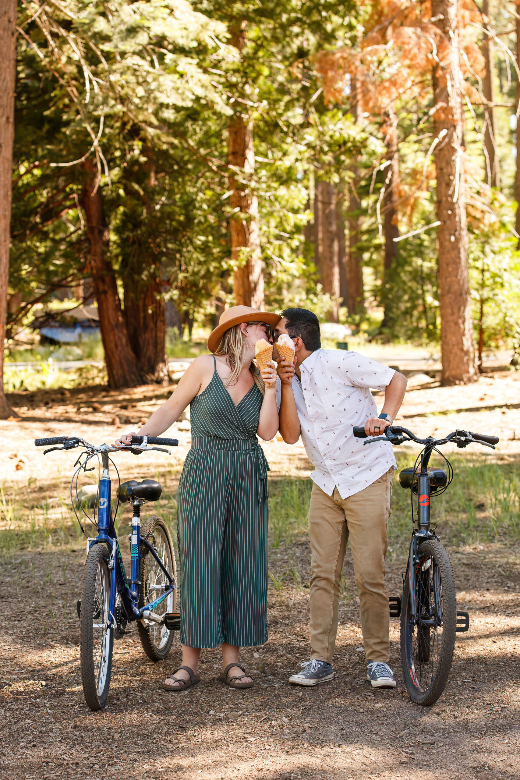 newly engaged couple holding up their ice cream cones while they kiss