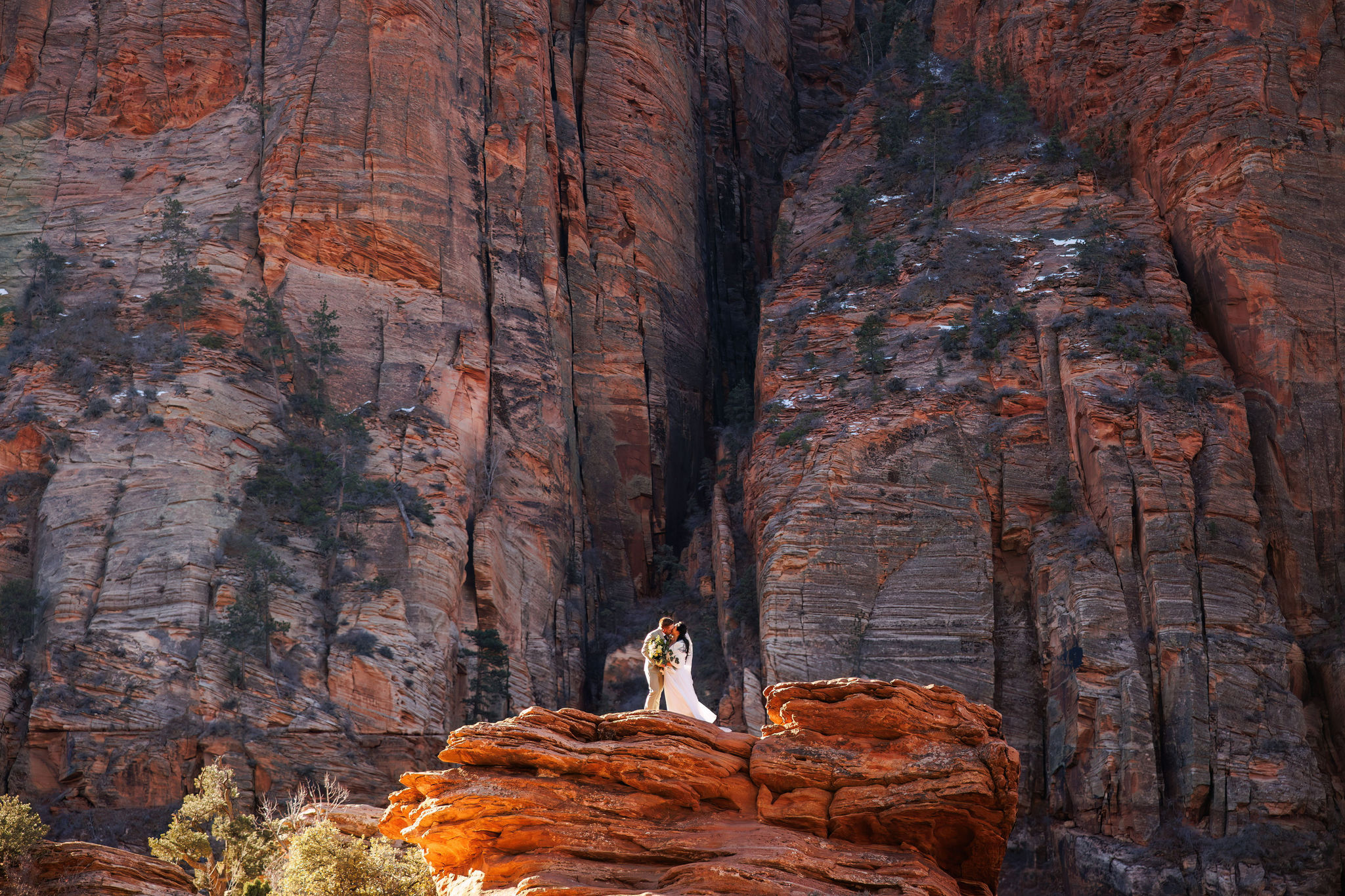 bride and groom kissing on a red rock in Zion 