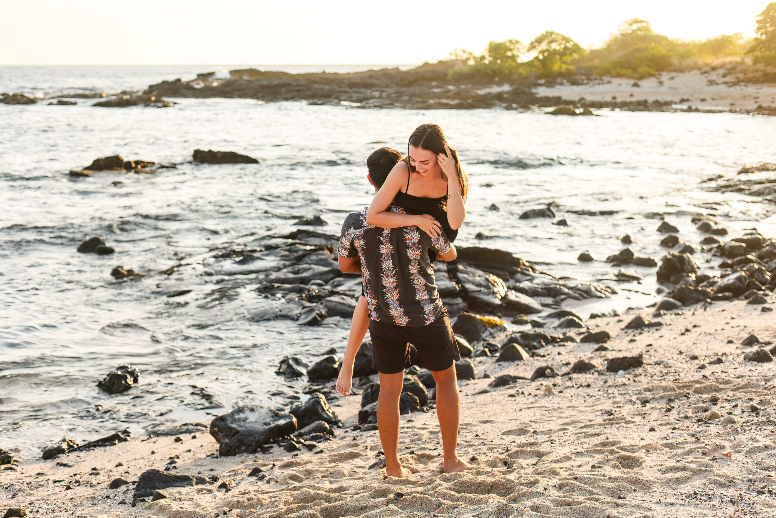 a man picking up a woman and walking on the beach