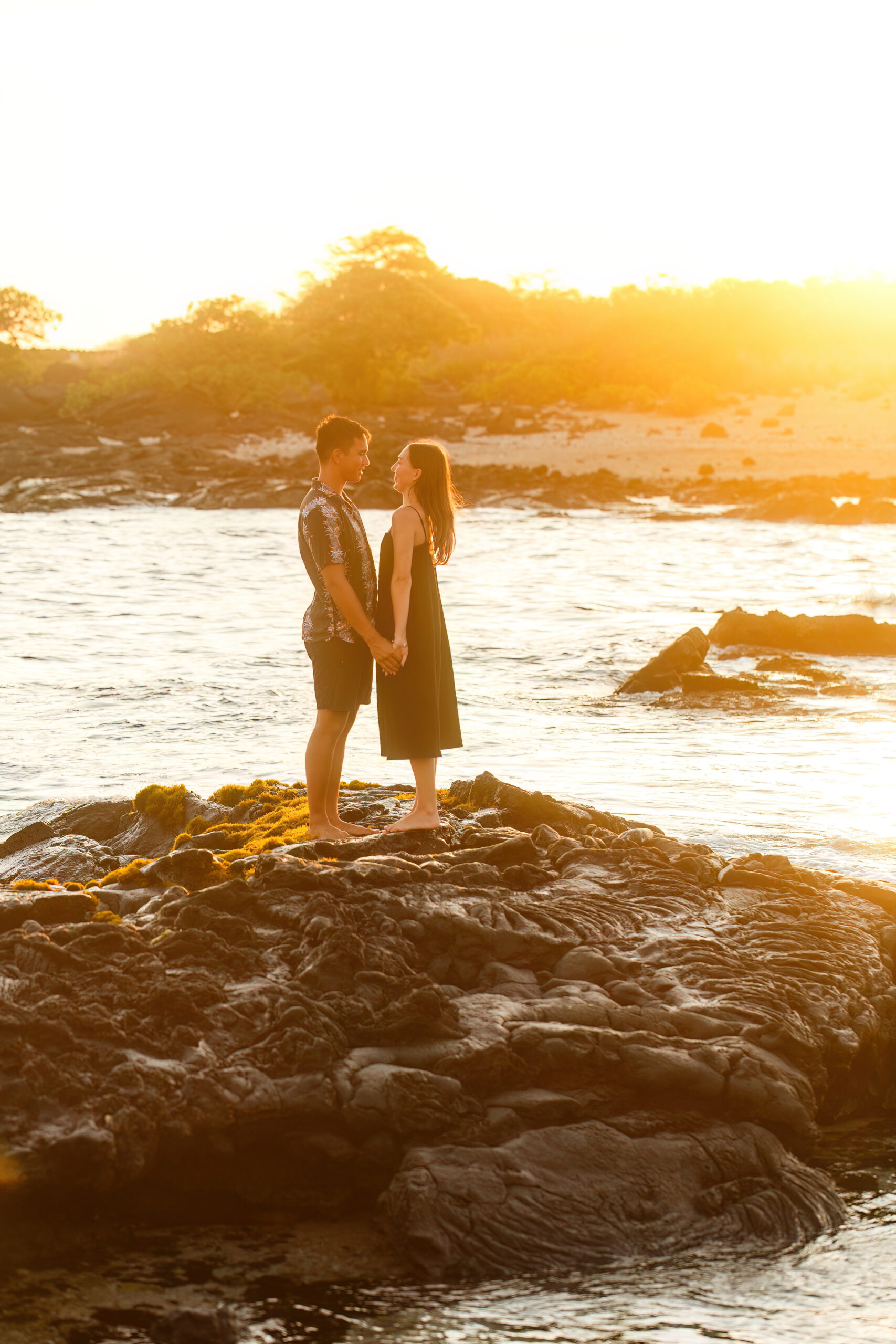 a couple standing together, holding hands on the beach in Hawaii