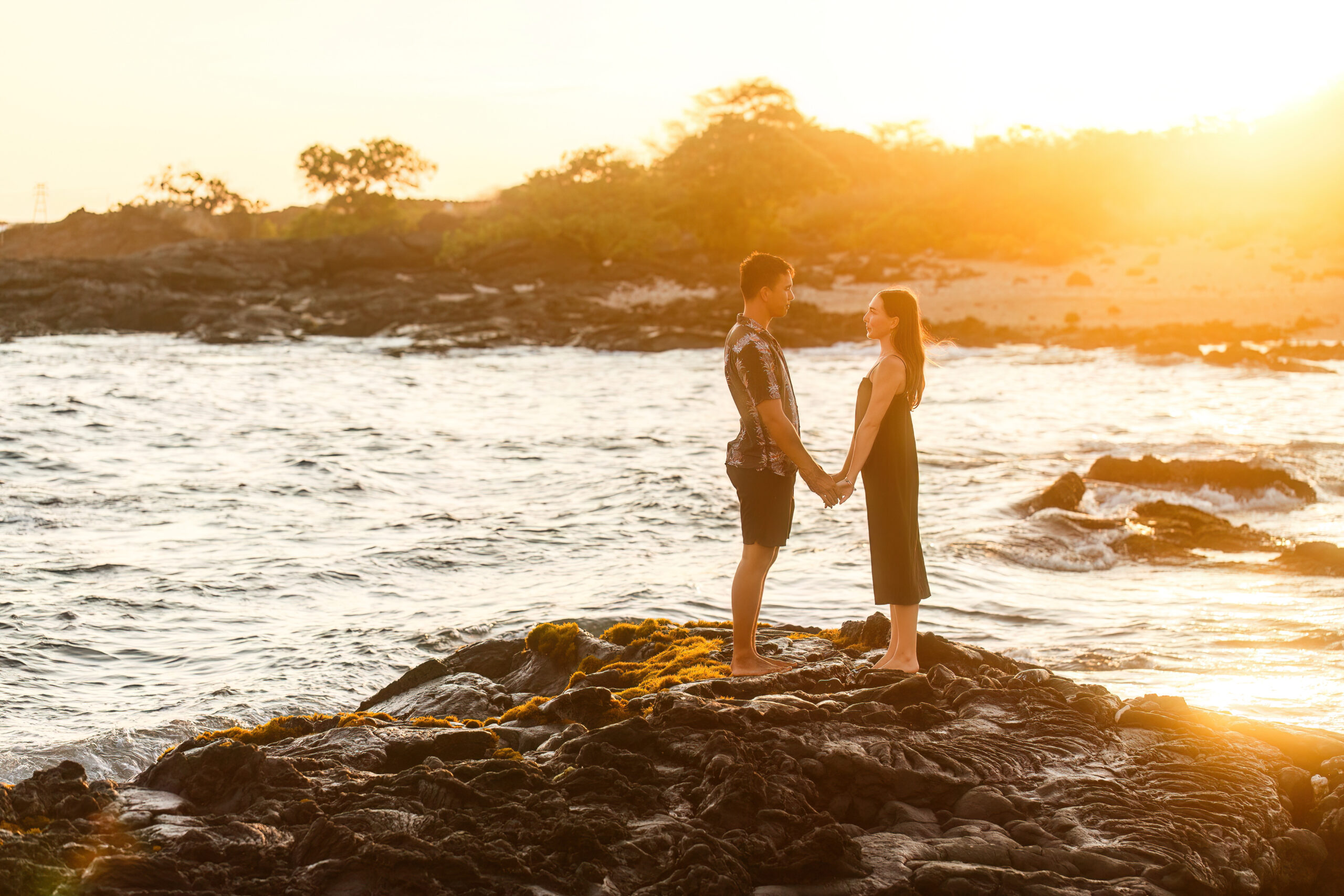 a couple holding hands and looking at each other during their beach Hawaiian elopement