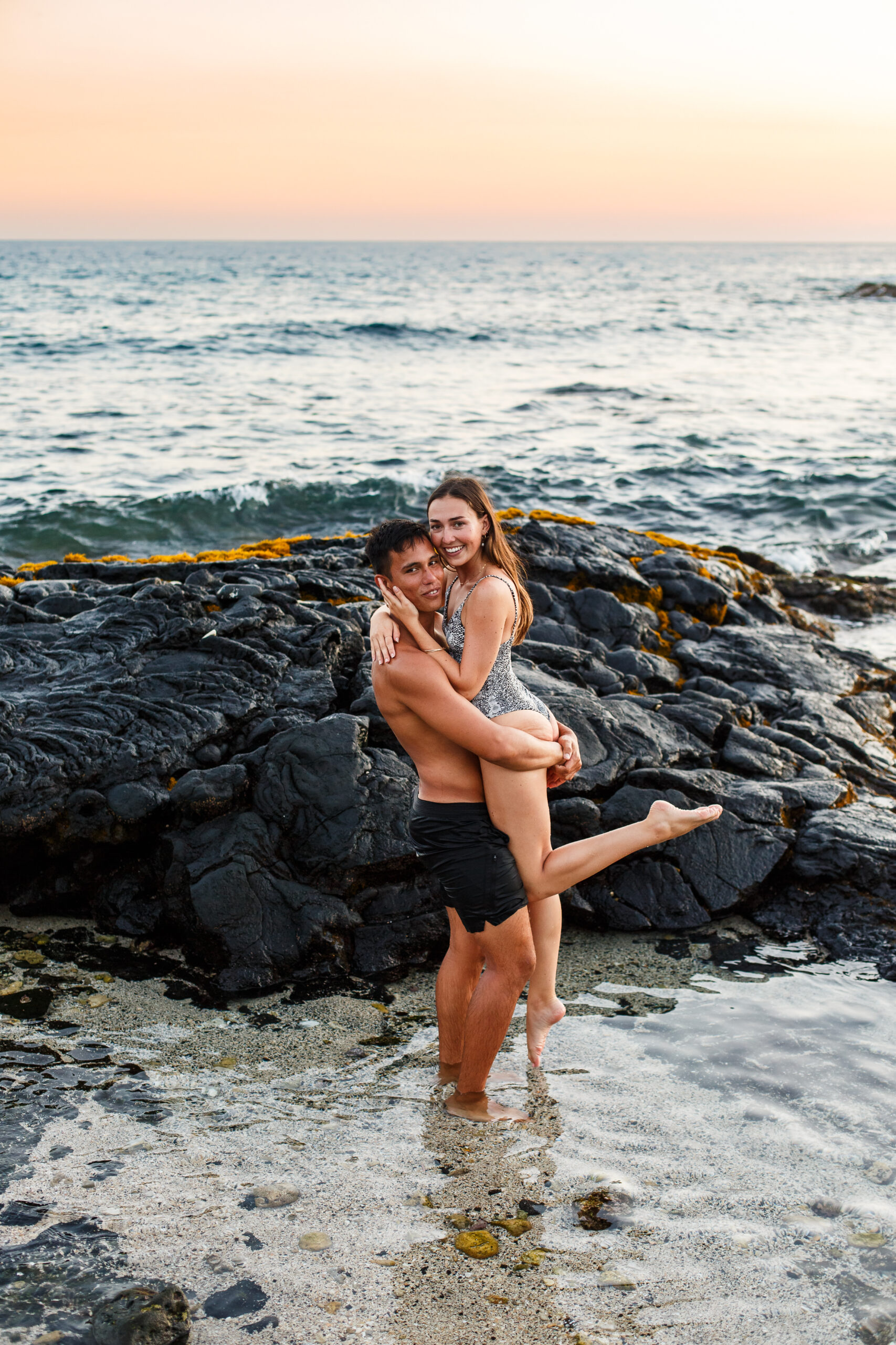 a man holding up a woman in the ocean