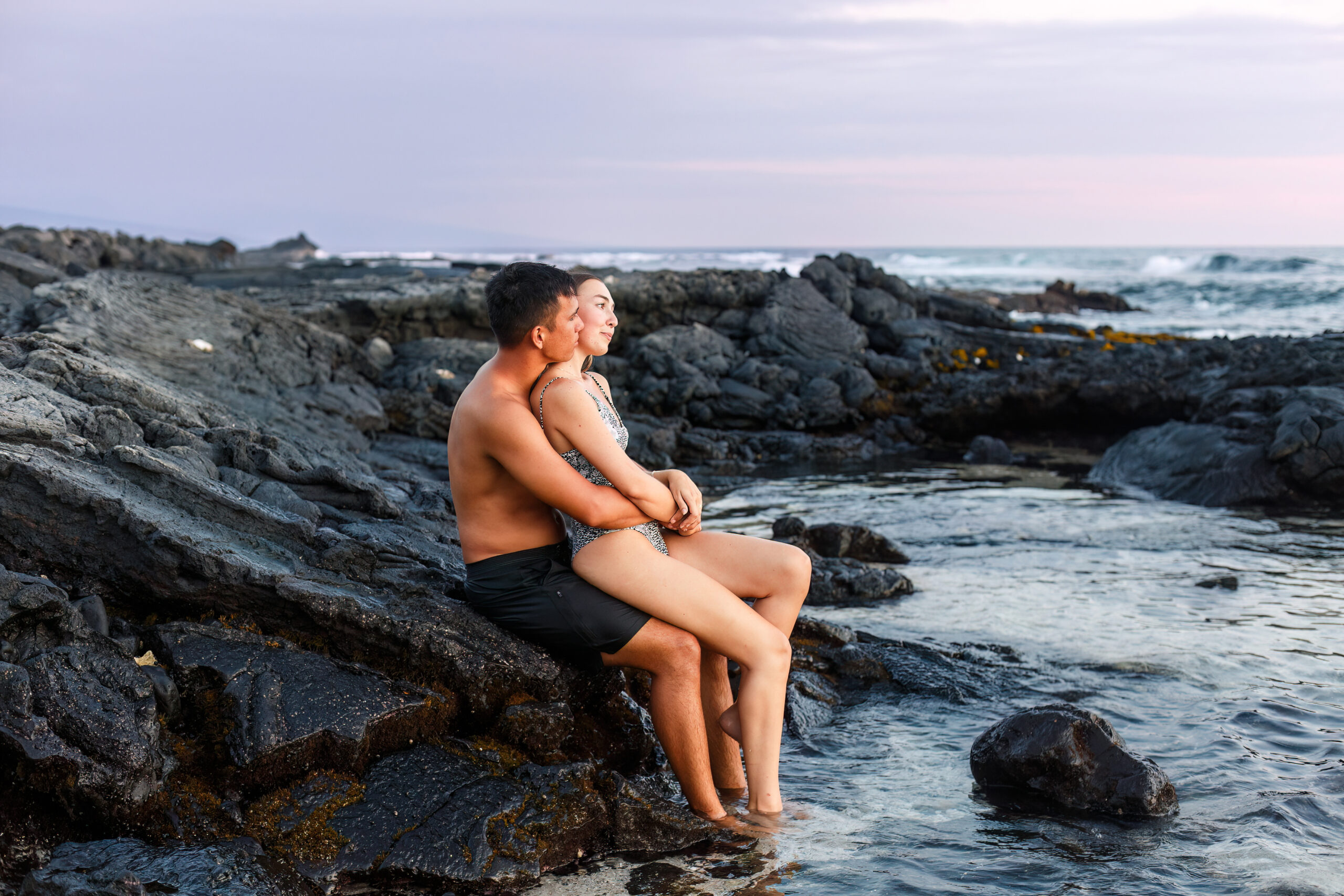 a couple sitting together in the ocean watching the sunset