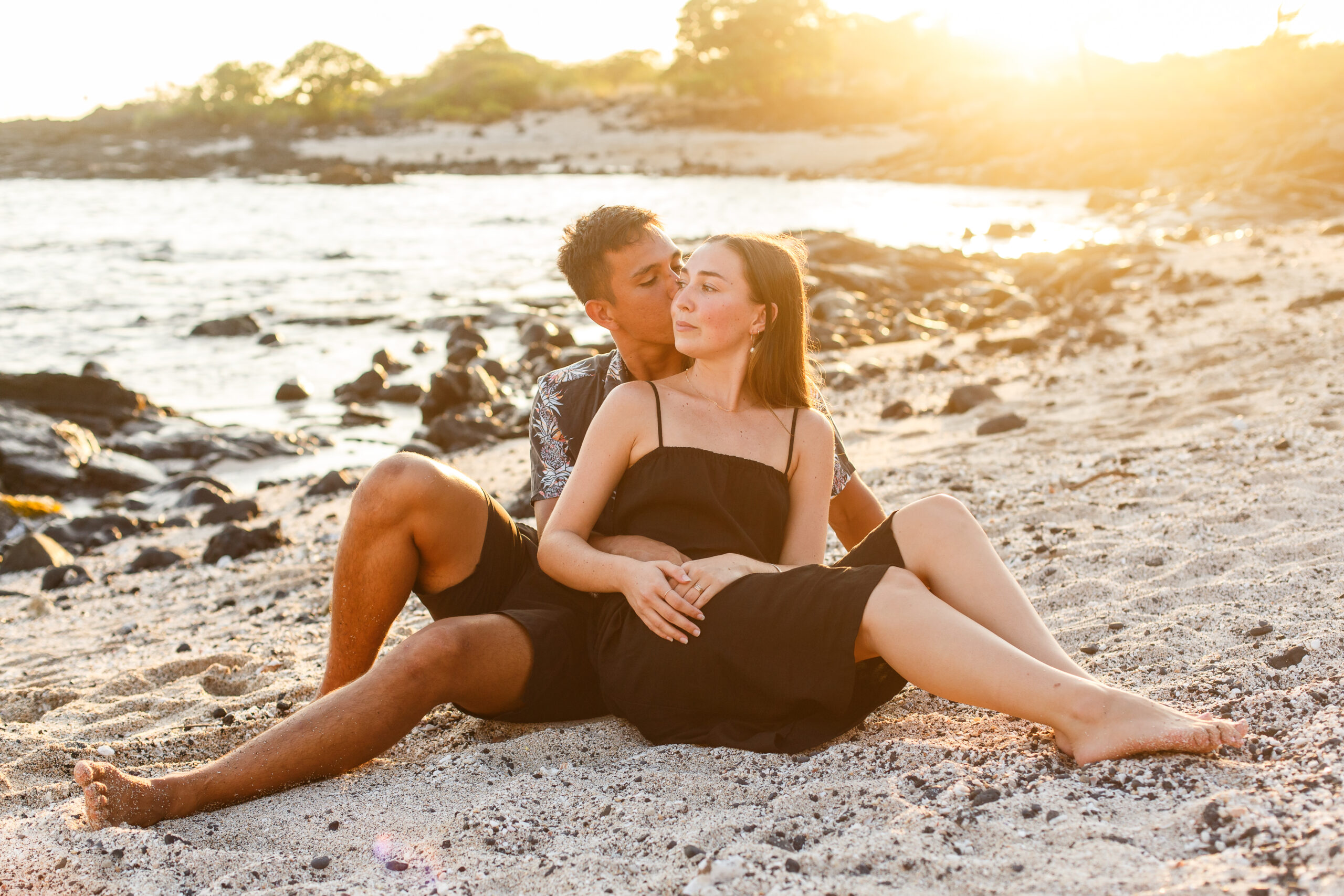 a couple sitting on a beach together at sunset