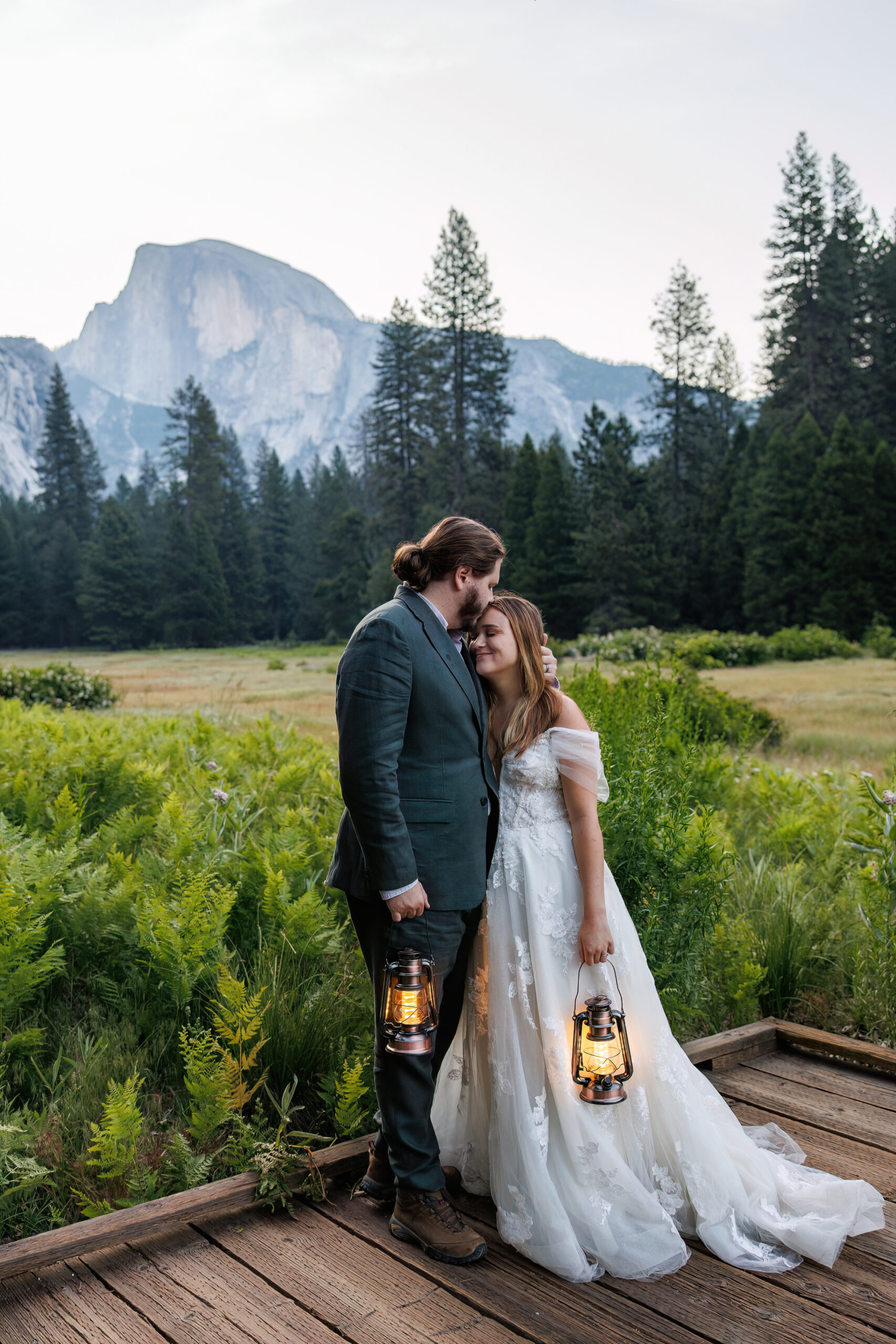 newly weds holding lanterns as they lean into each other for Yosemite wedding photos