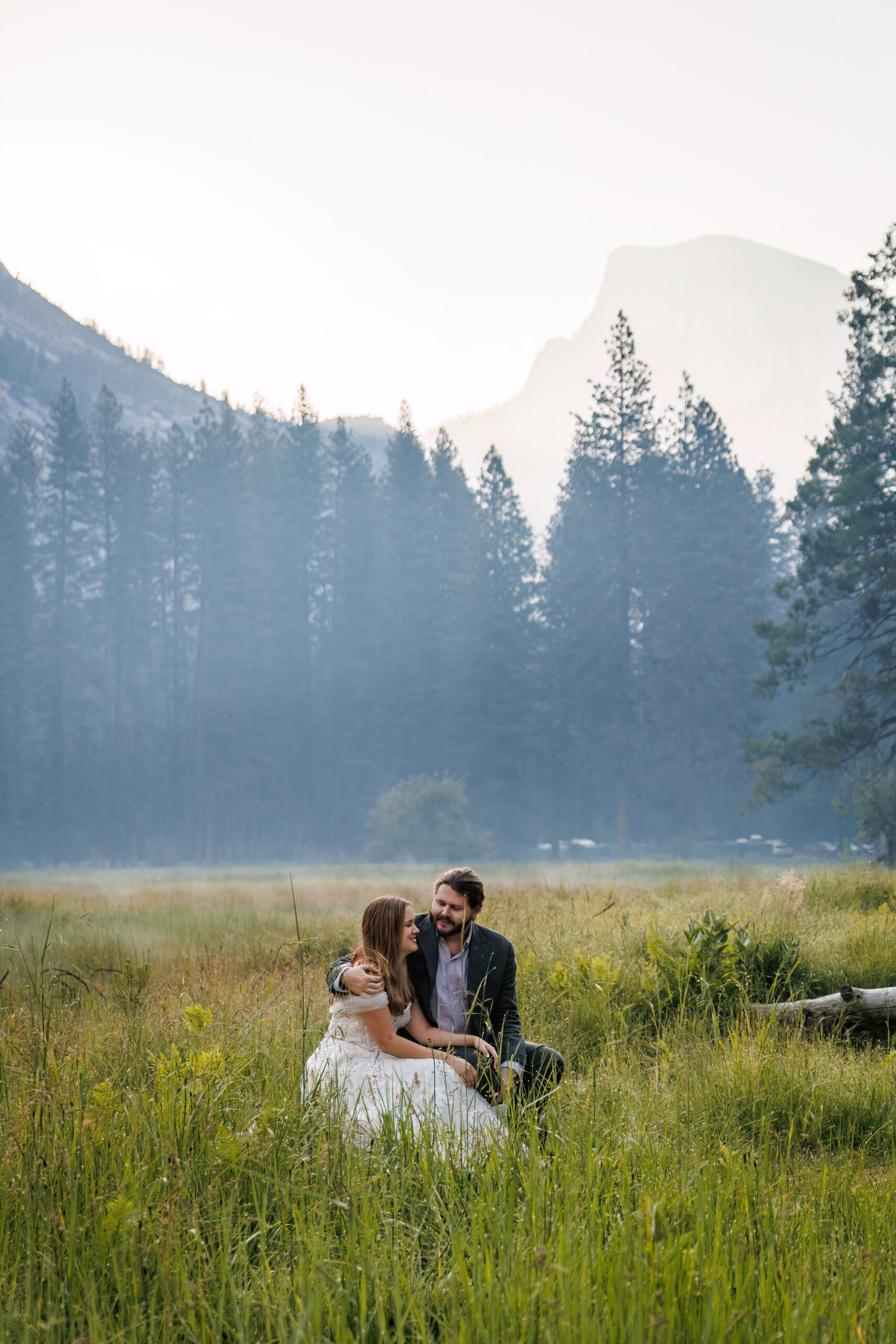 newly weds sitting in a meadow in Yosemite during their after session