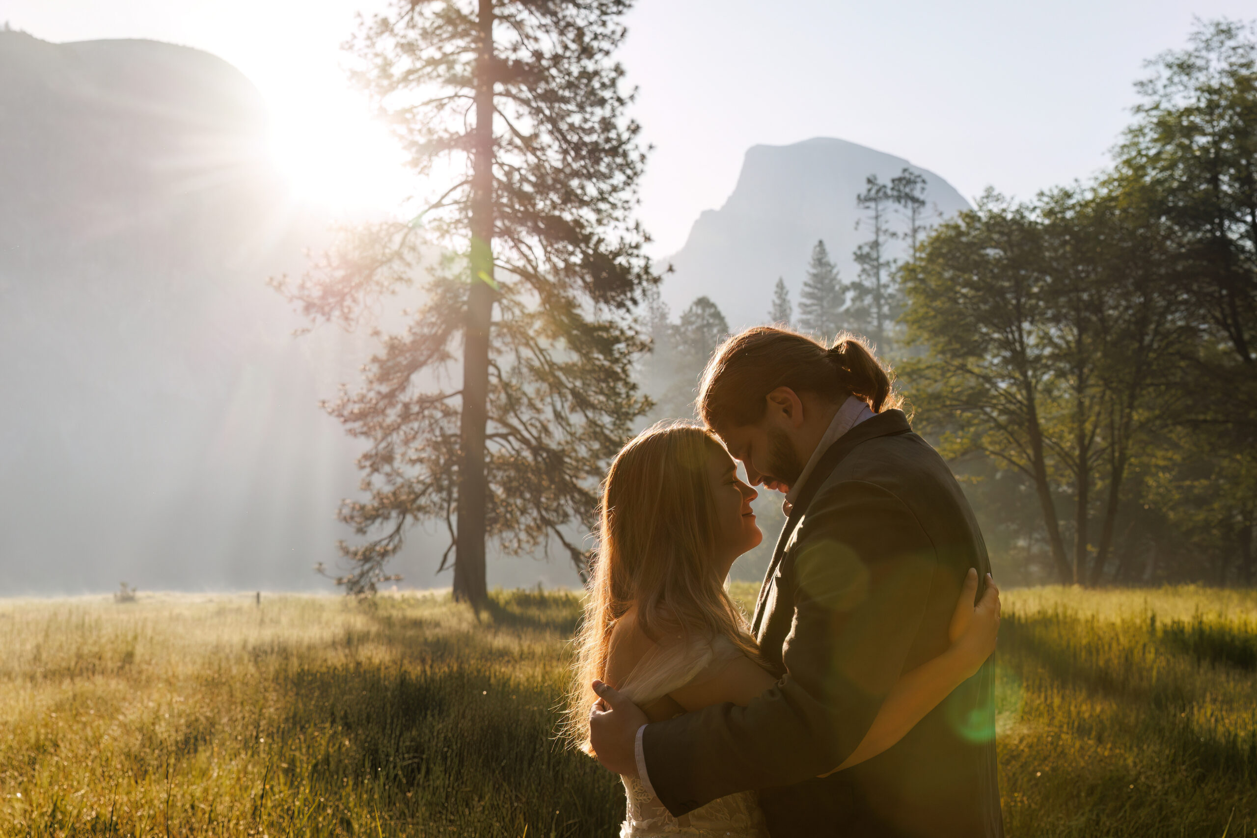 the sun peaking over the mountains as they couple embrace during Yosemite wedding photos