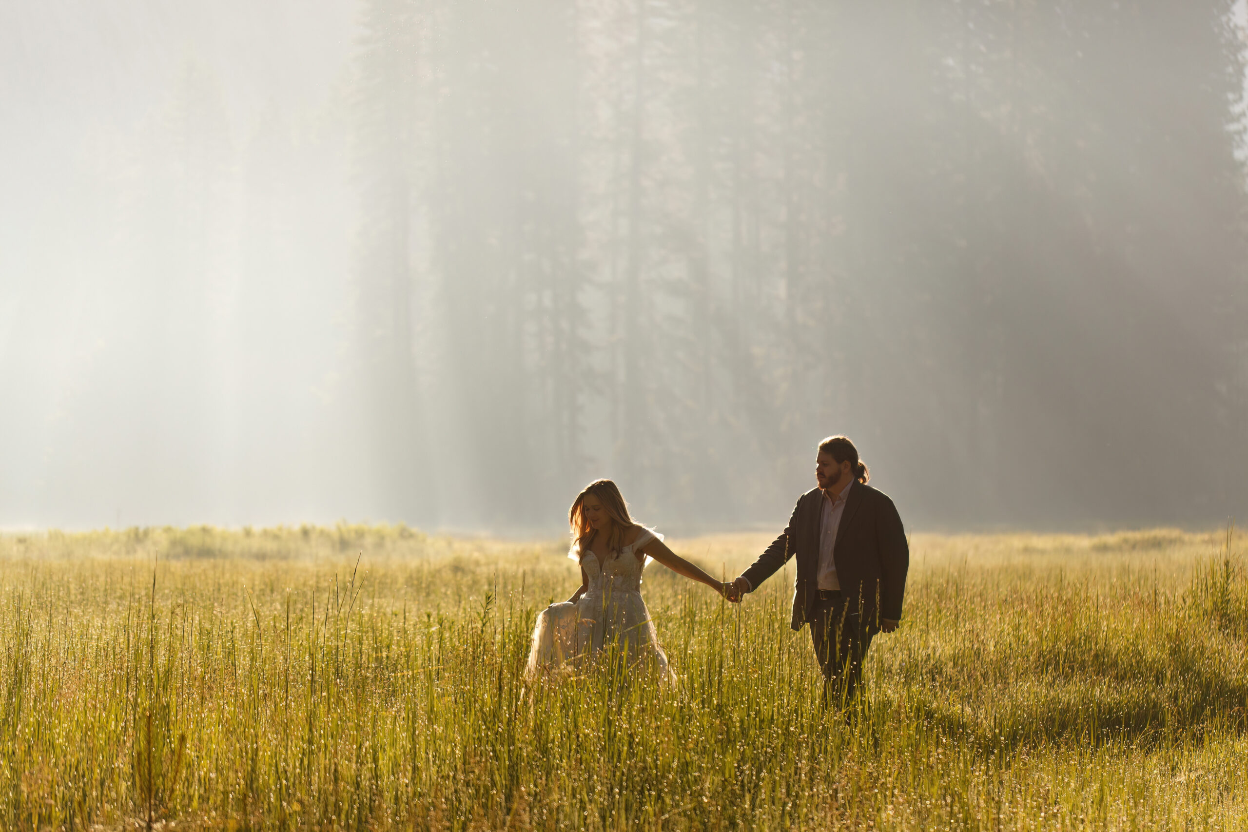 a couple walking hand in hand through the grass during their Yosemite wedding photos