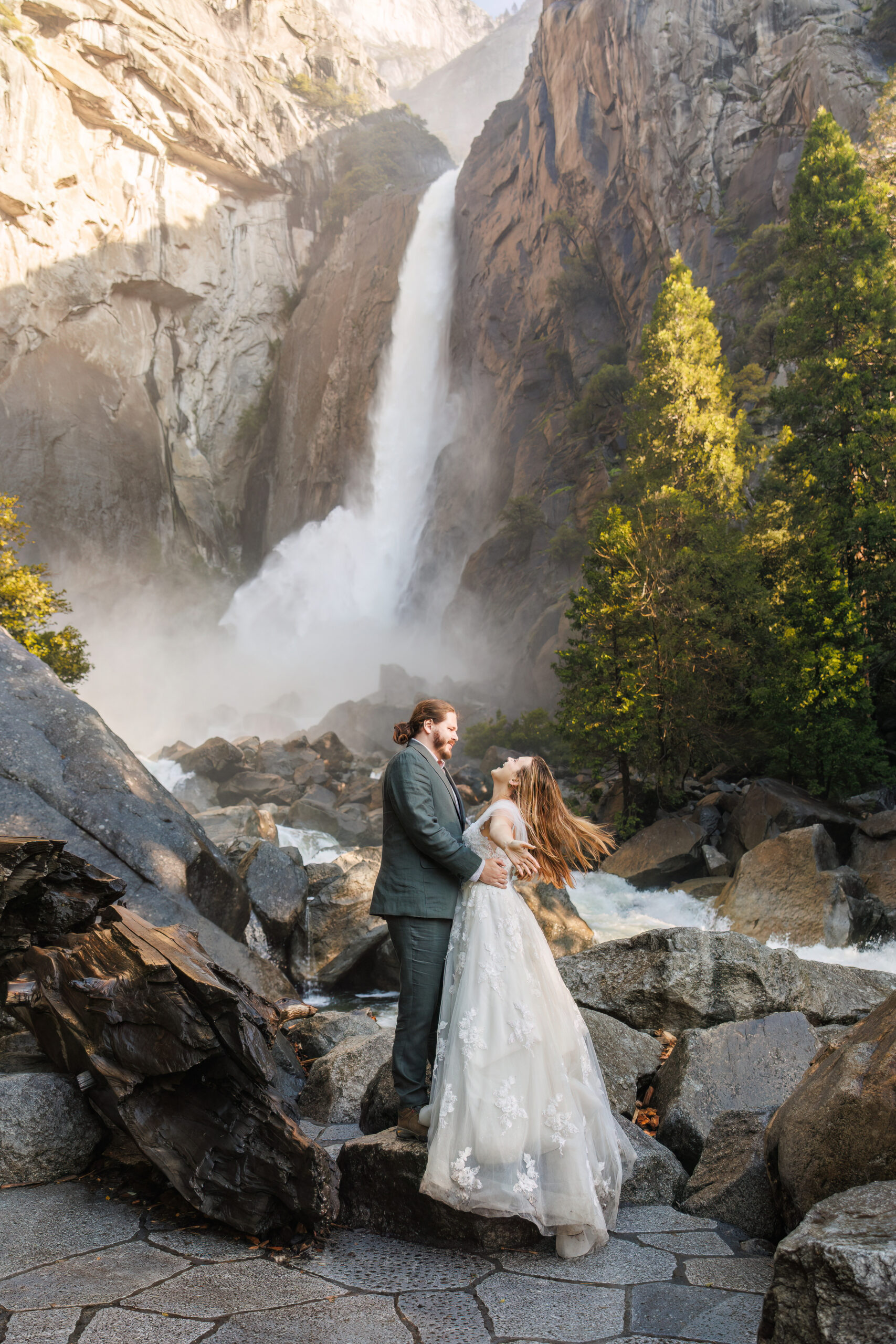newly weds standing in front of a waterfall for Yosemite wedding photos