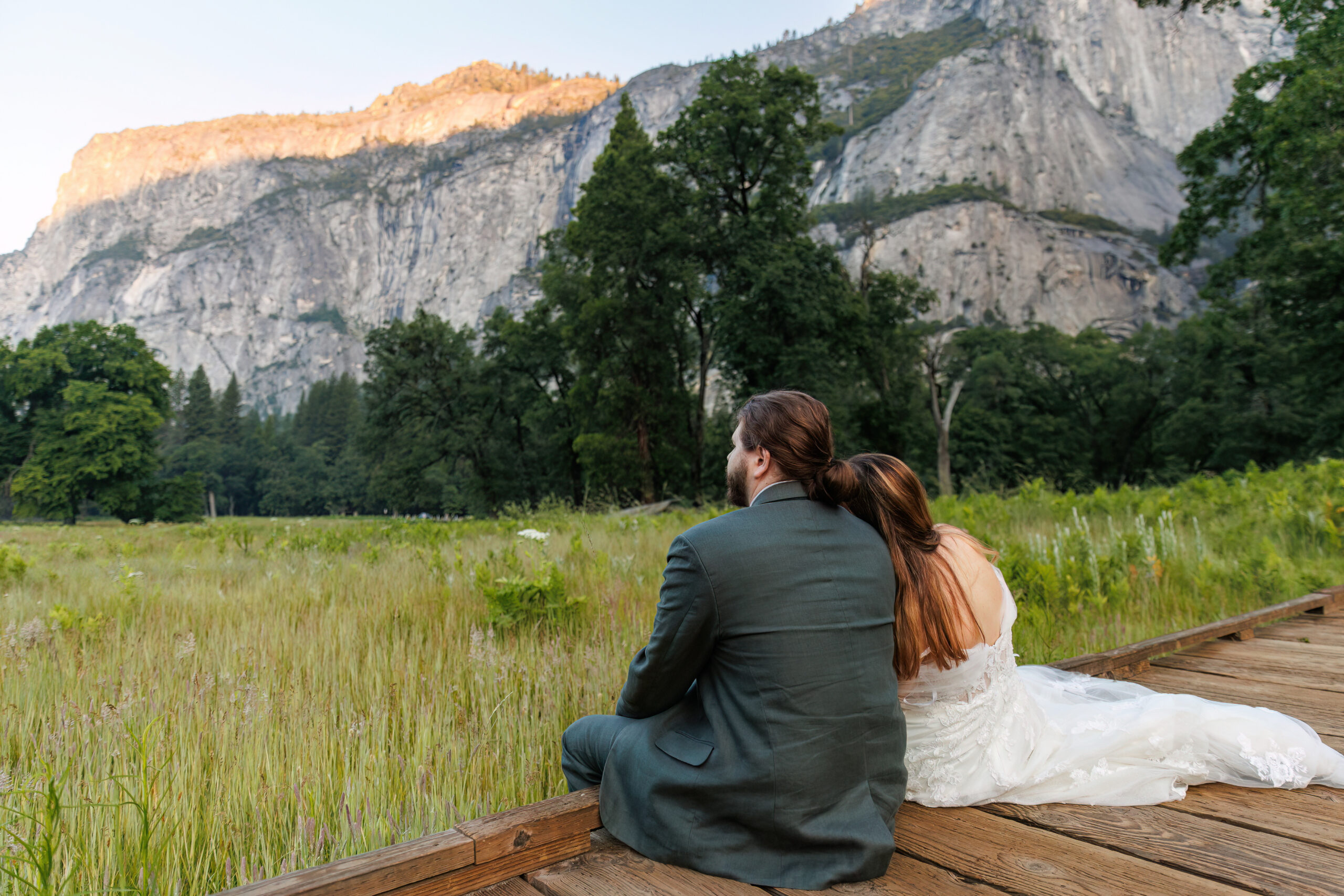 newly weds sitting on a wooden bridge together admiring the view