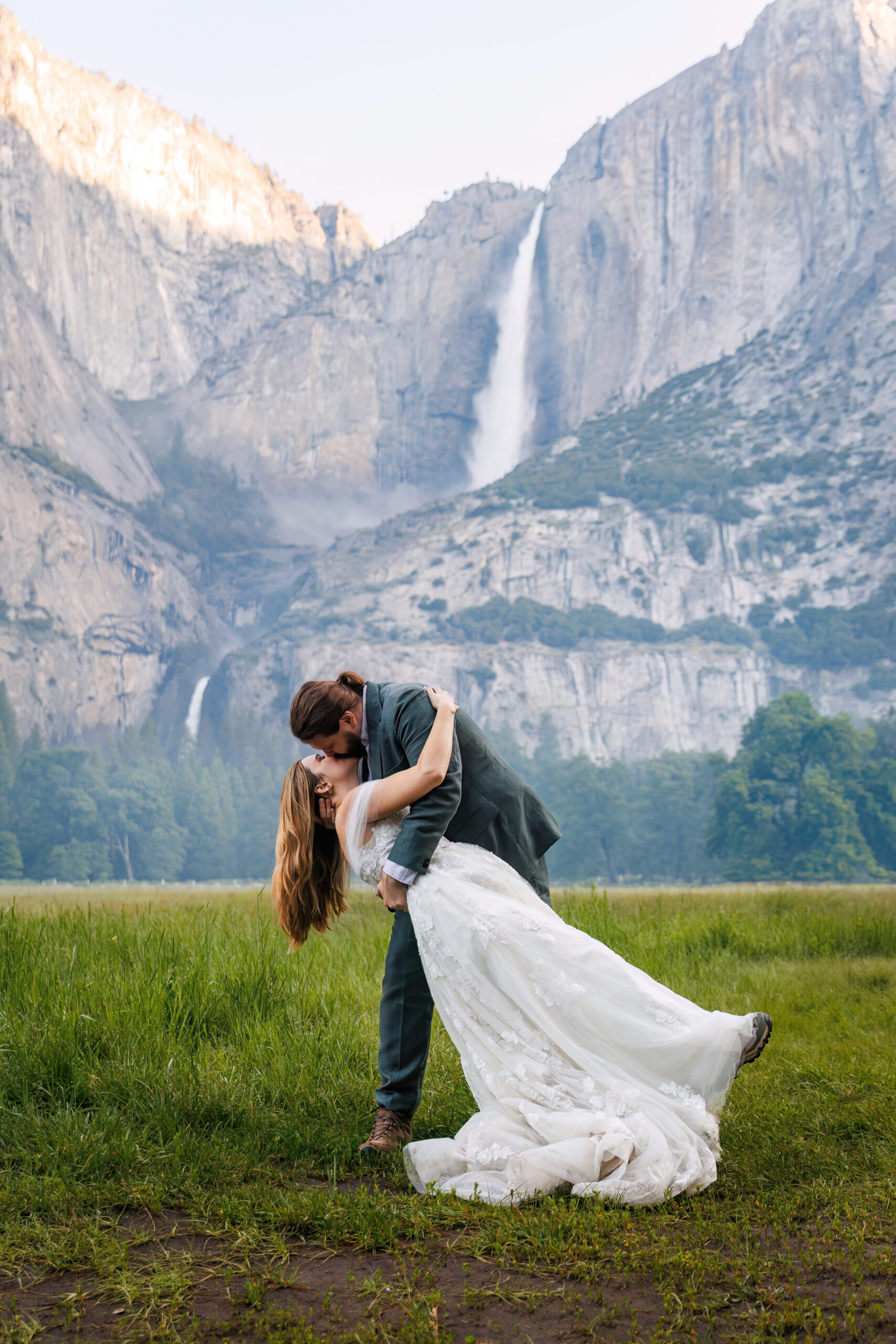 a man dipping a woman as he kisses her in front of a waterfall for Yosemite wedding photos