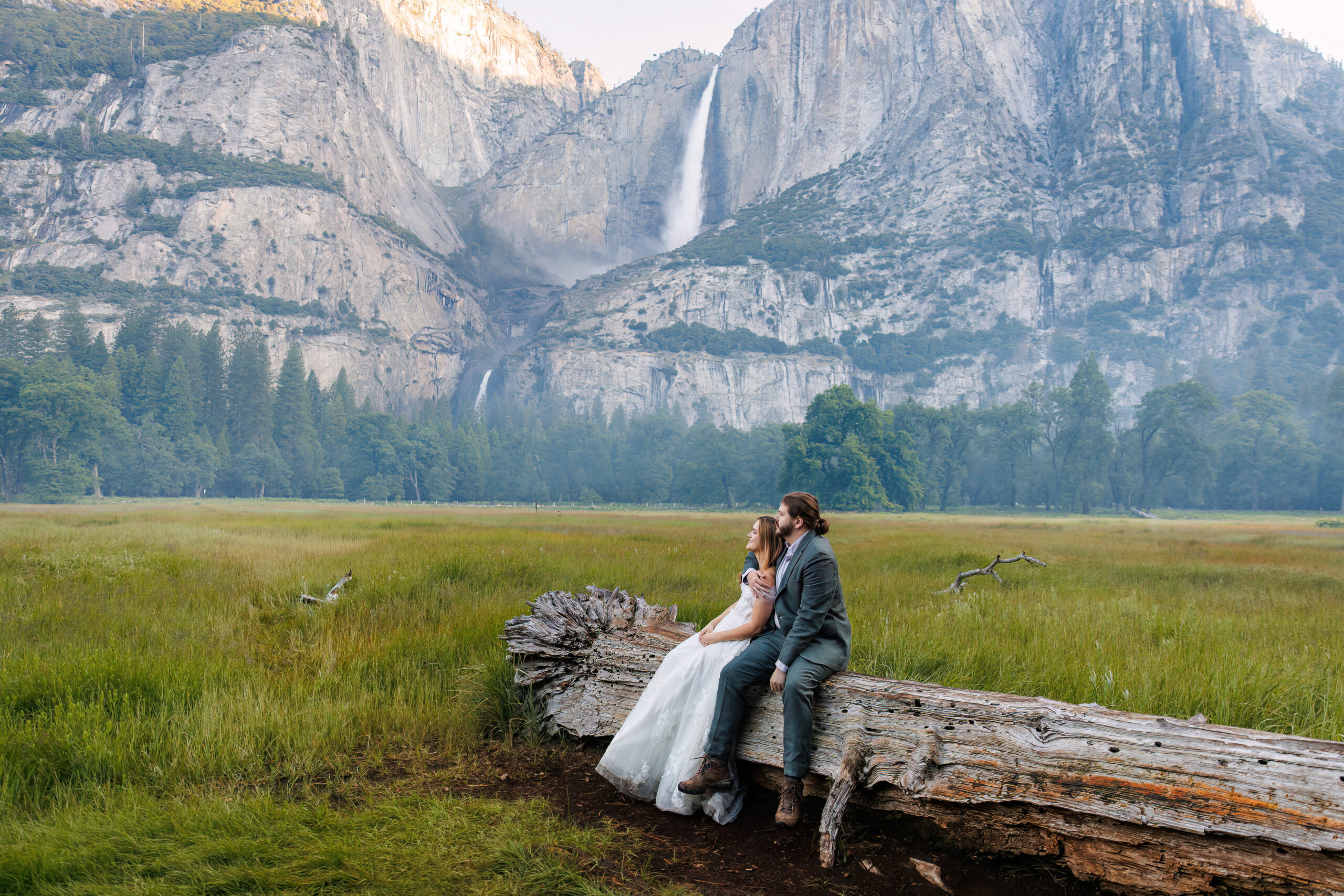 newly weds sitting on a fallen tree for Yosemite wedding photos
