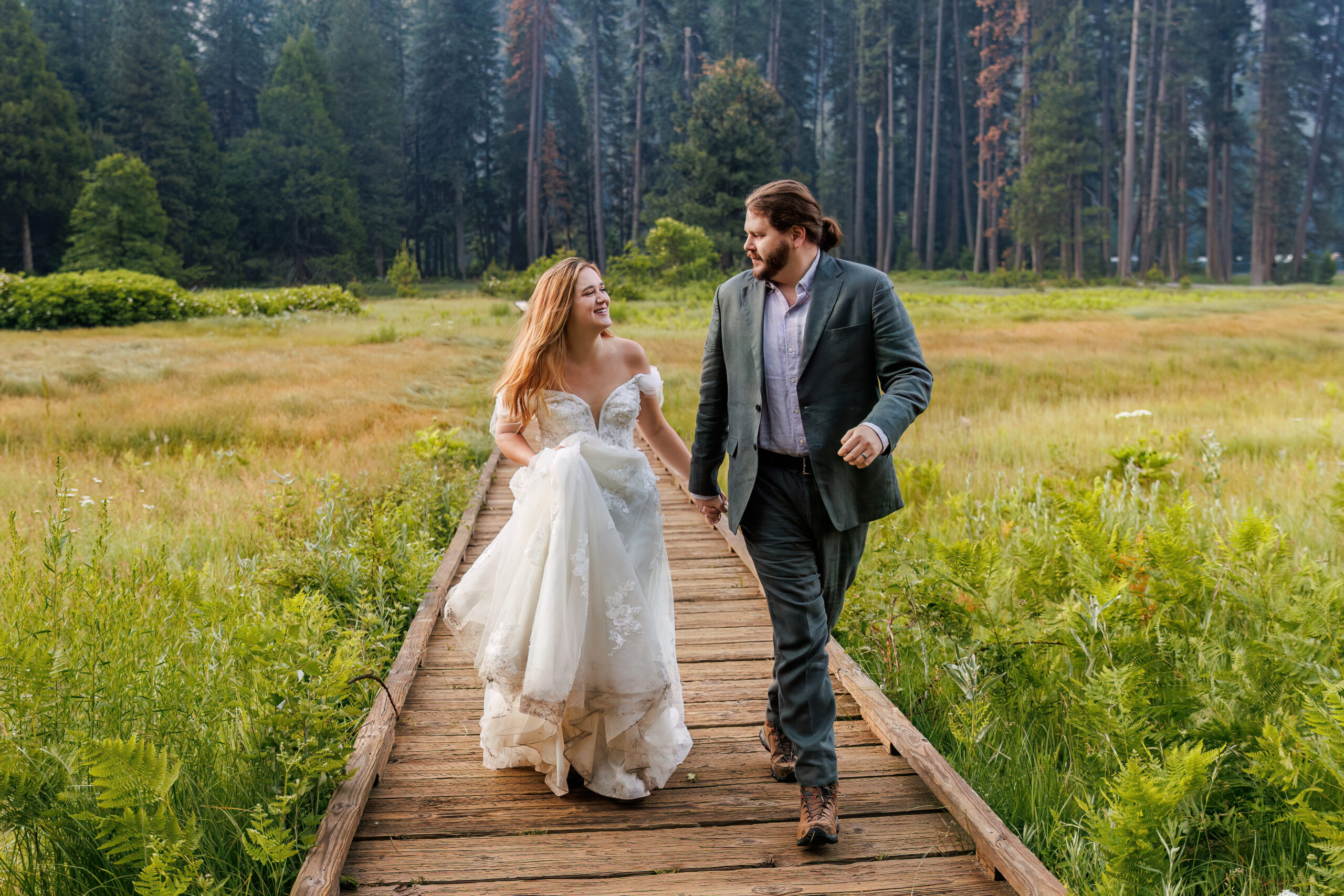 newly weds in their wedding attire walking on a wooden path in Yosemite