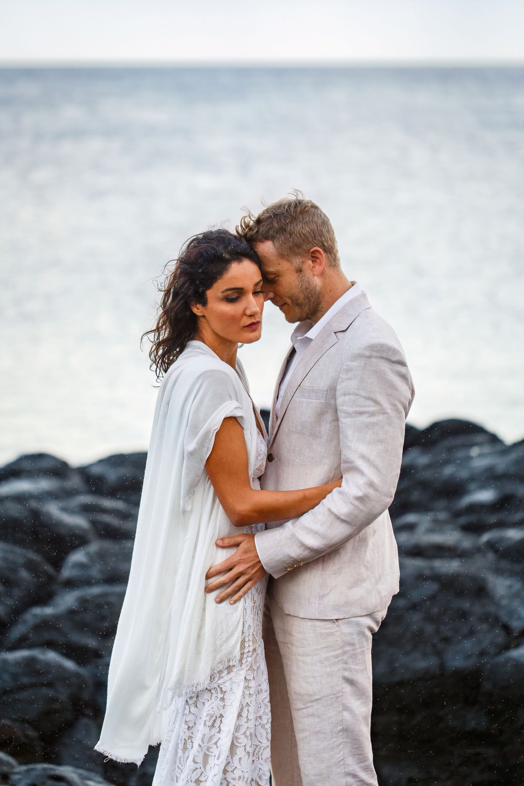 a couple on the beach cuddling into each other during their Hawaiian elopement