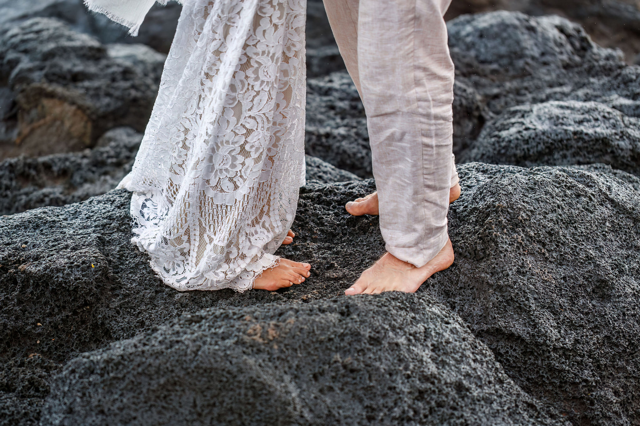 newly weds feet as they stand together on black rocks for their Hawaiian elopement