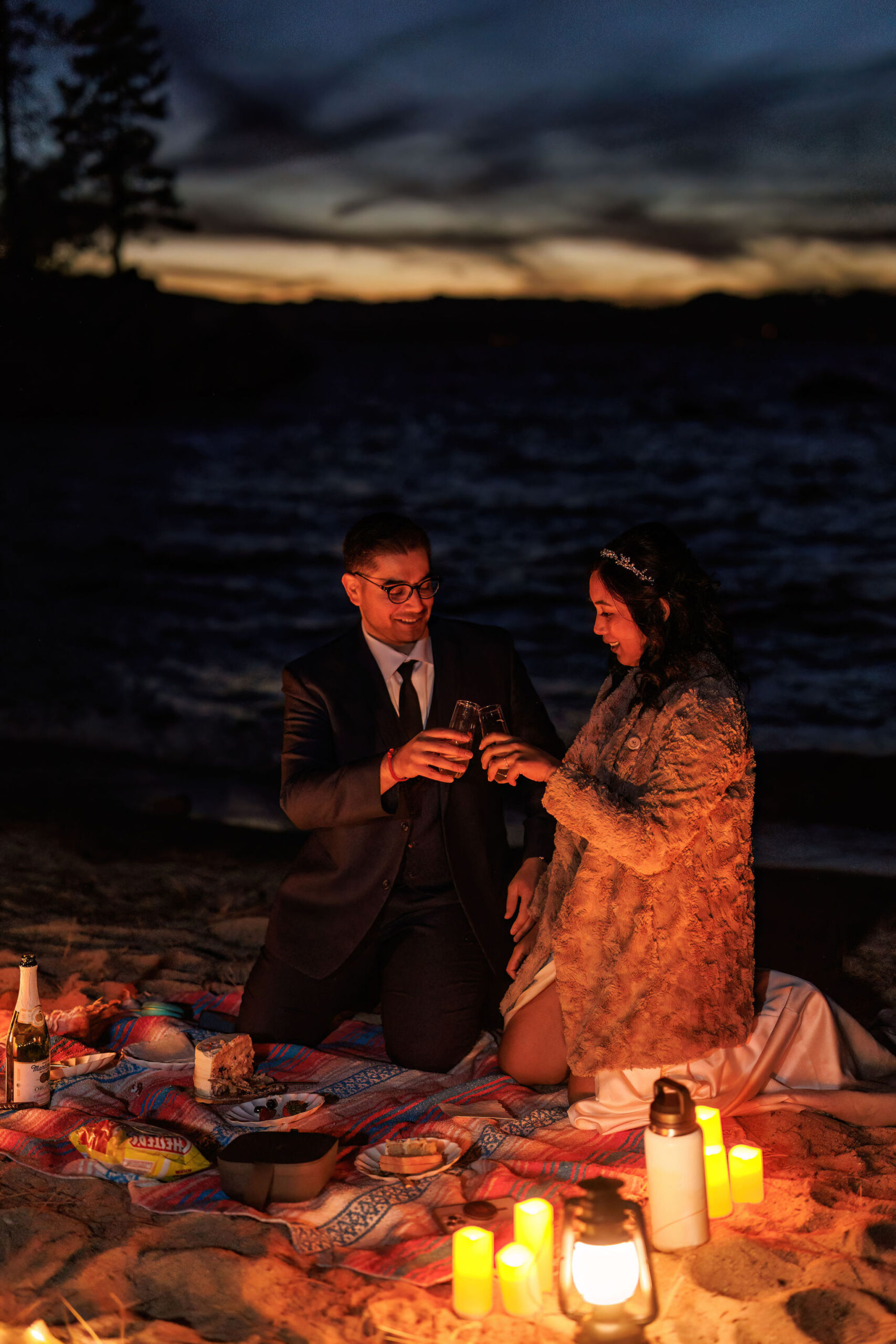 a couple enjoying a beach picnic with candles at night