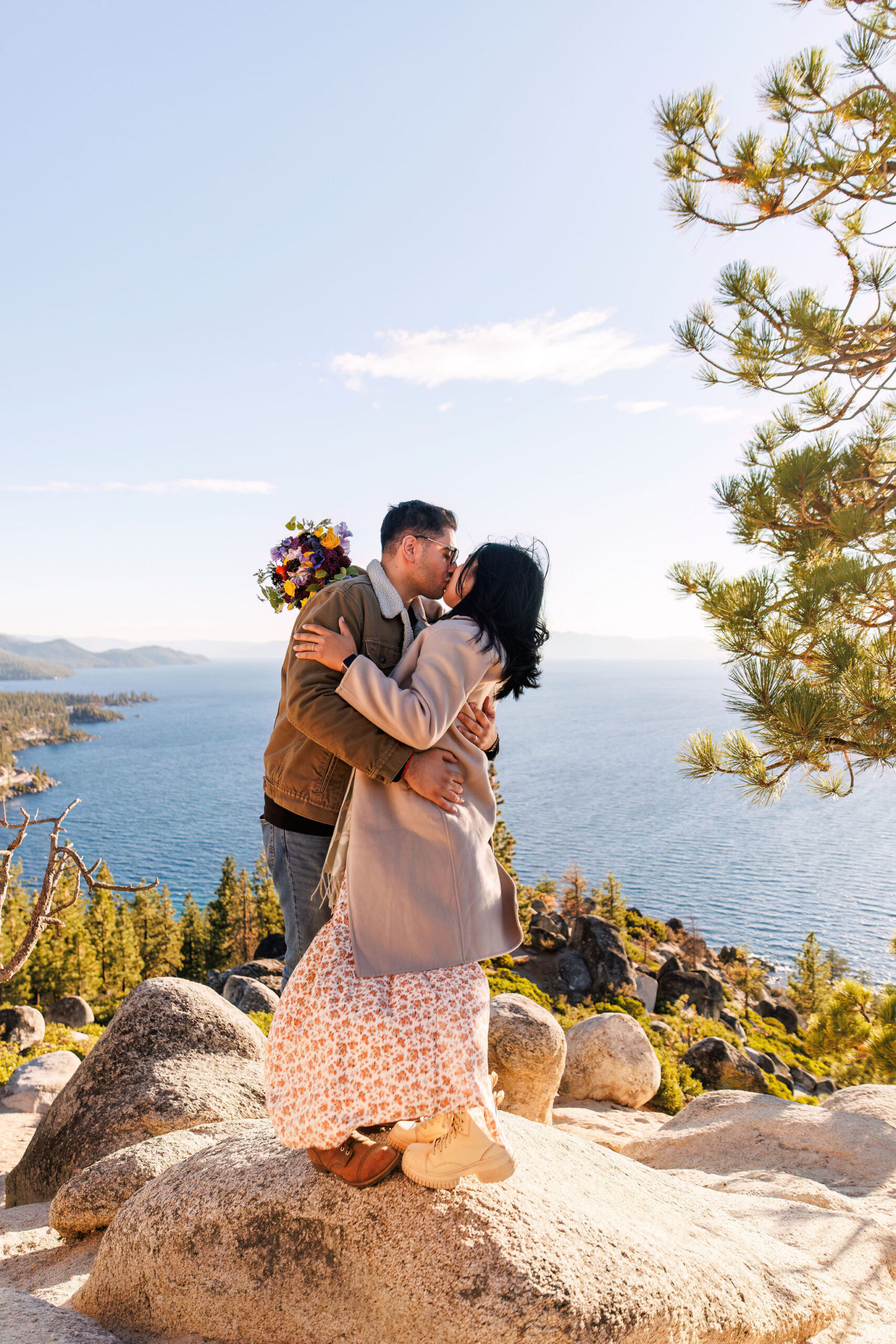newly weds kissing on a rock about the lake during their adventure elopement