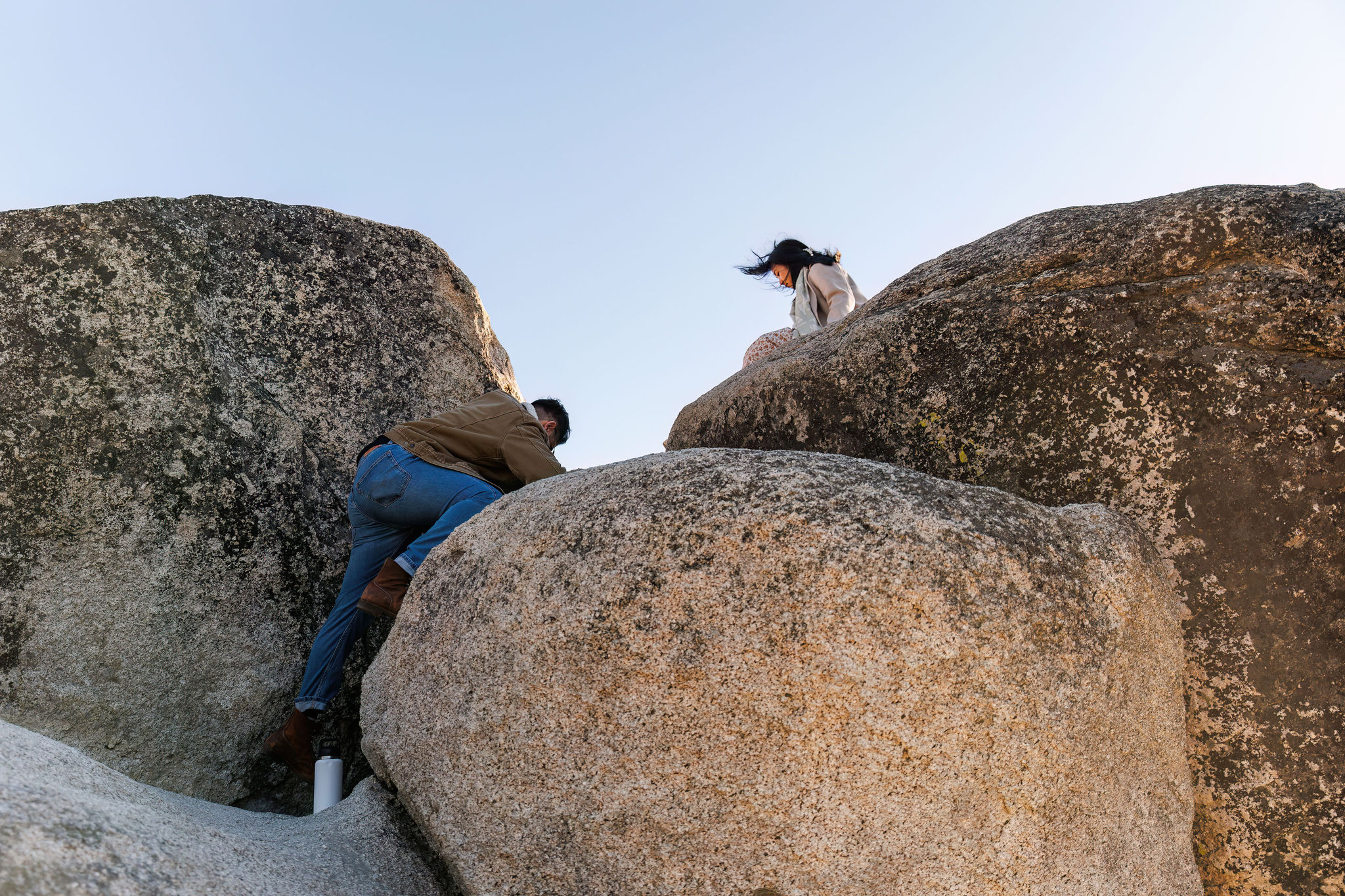 newly weds climbing up boulders to get to the view during their adventure elopement