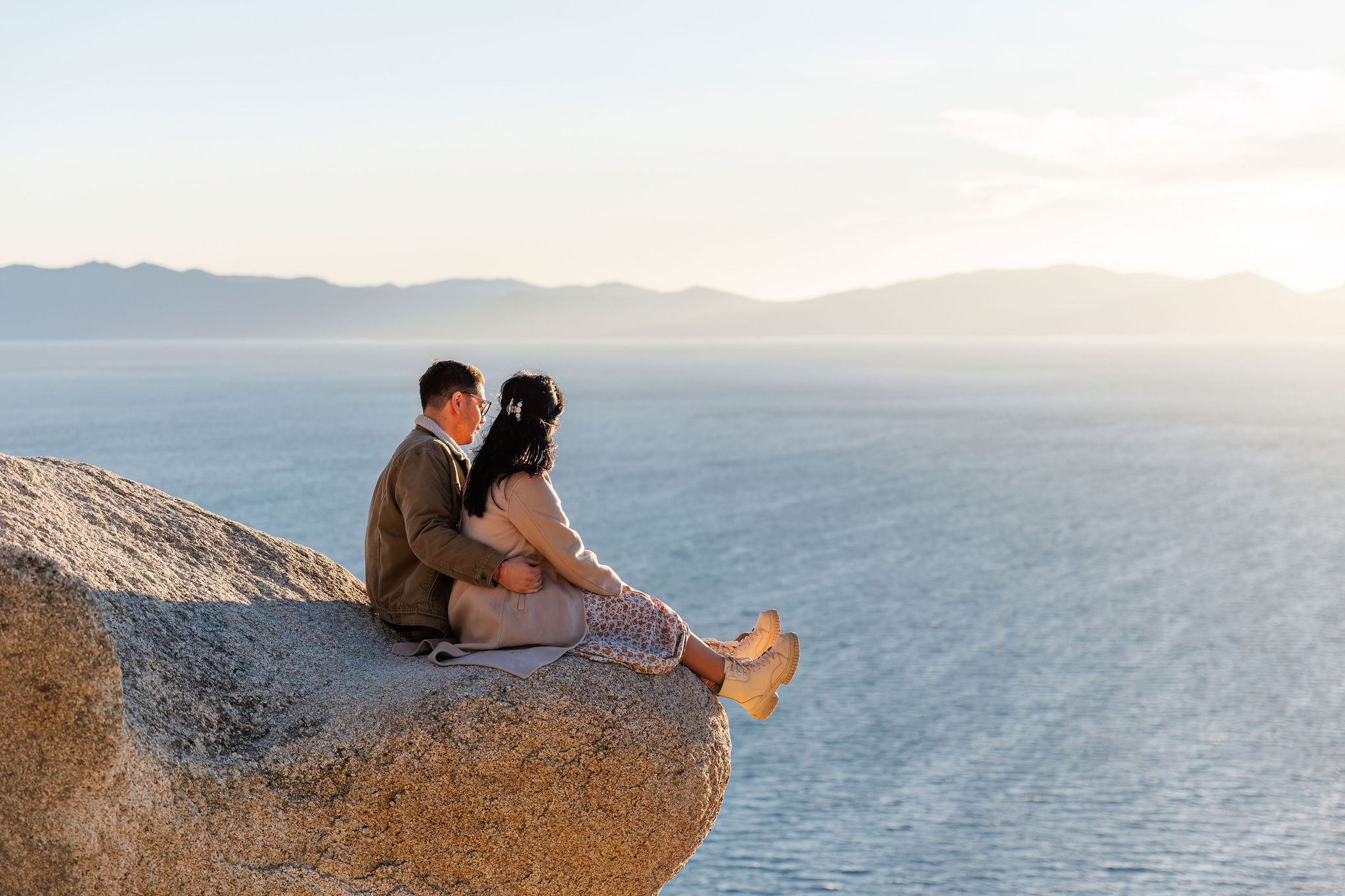 a couple sitting on a cool rock look out about Lake Tahoe
