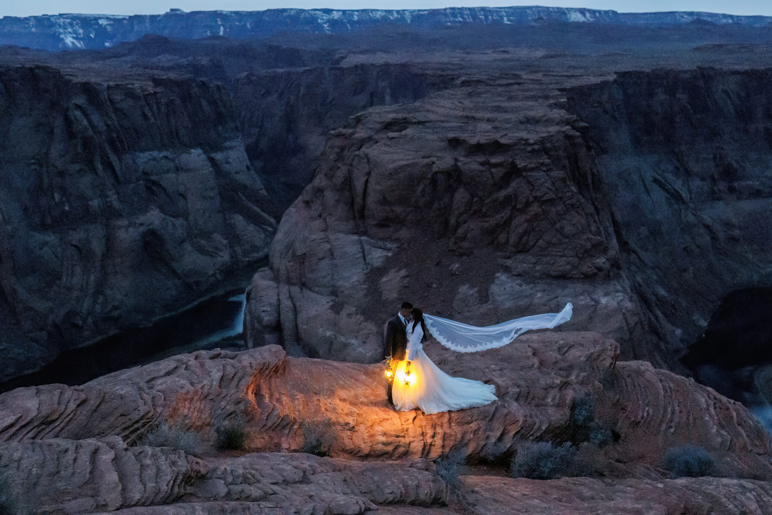 newly weds at dark, holding lanterns in an epic location