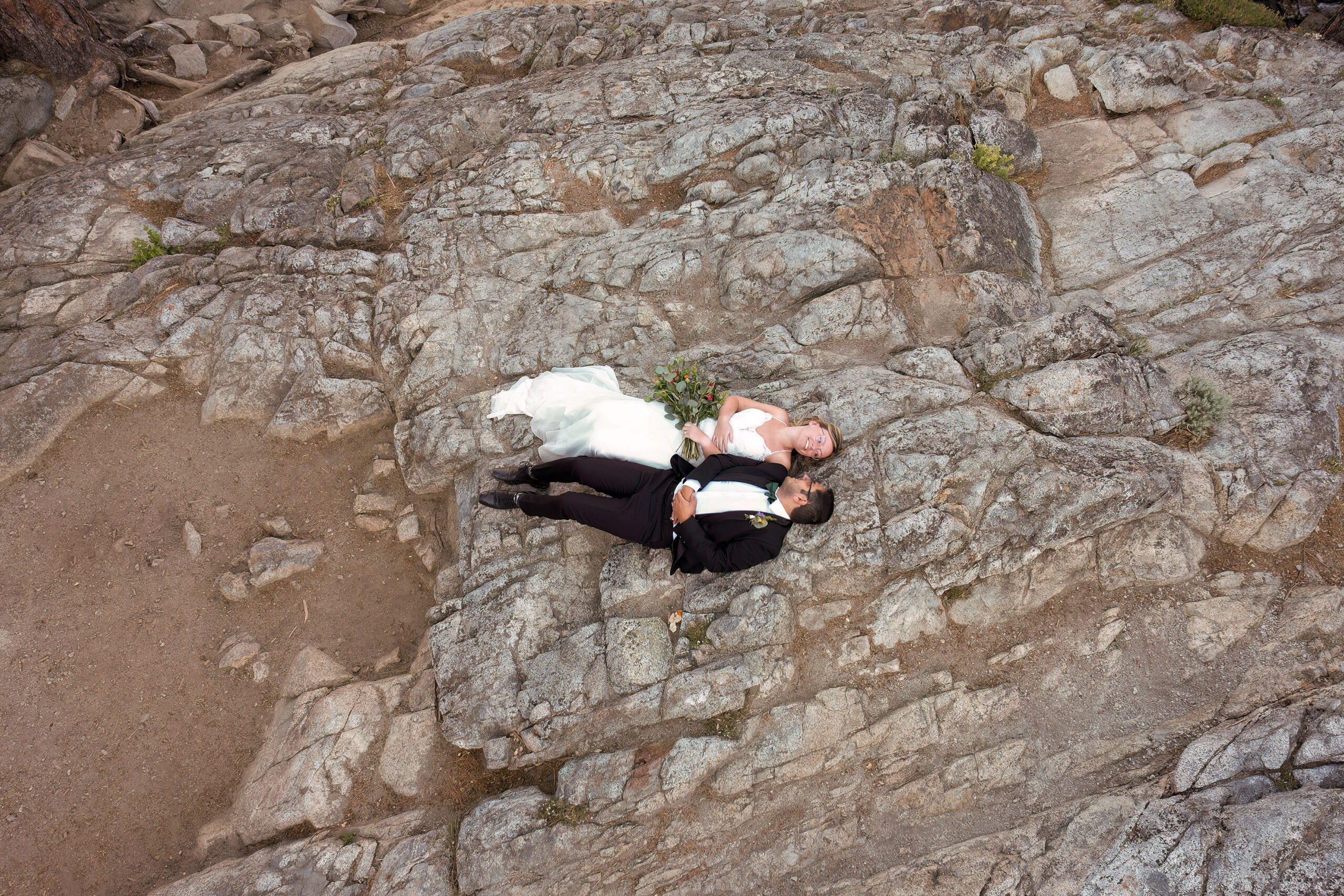 a couple taking a break in their elopement timeline and laying on the rock ground together