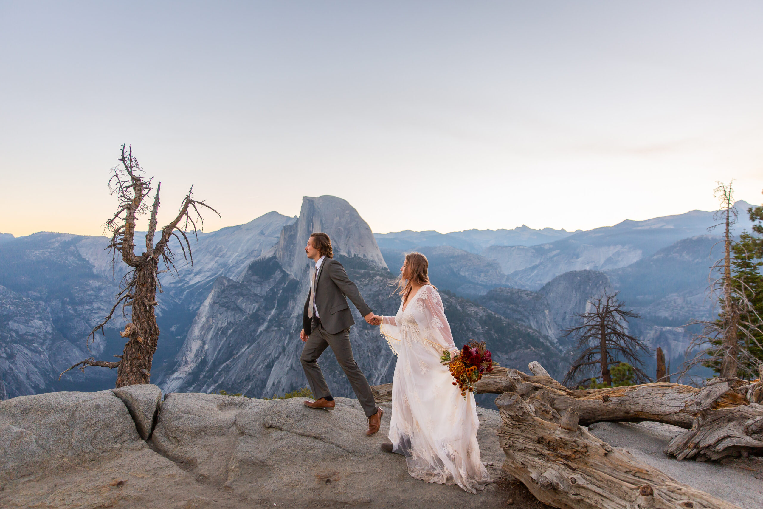 a couple walking hand in hand on top of a mountain