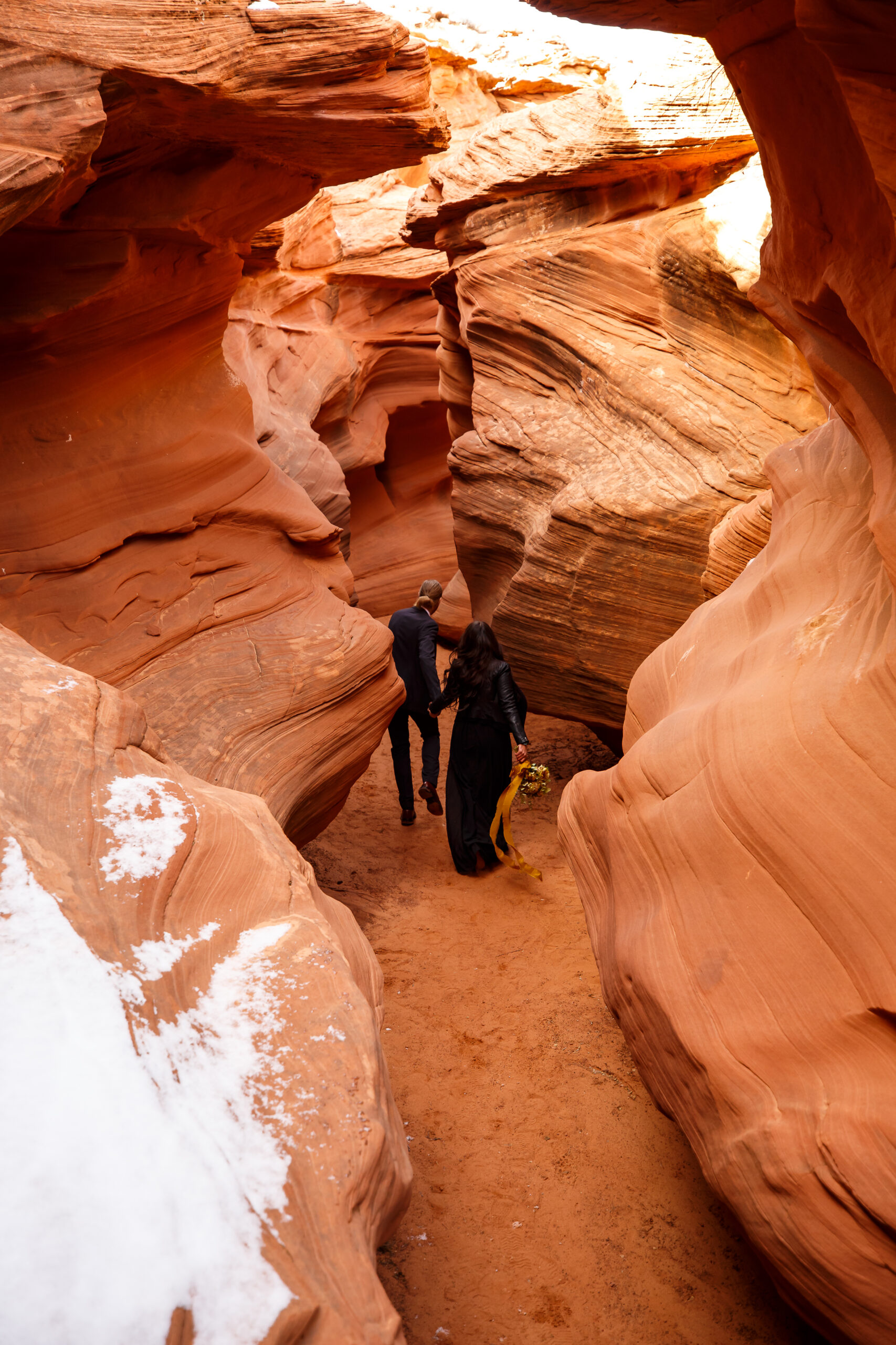 a couple walking through a slot canyon together