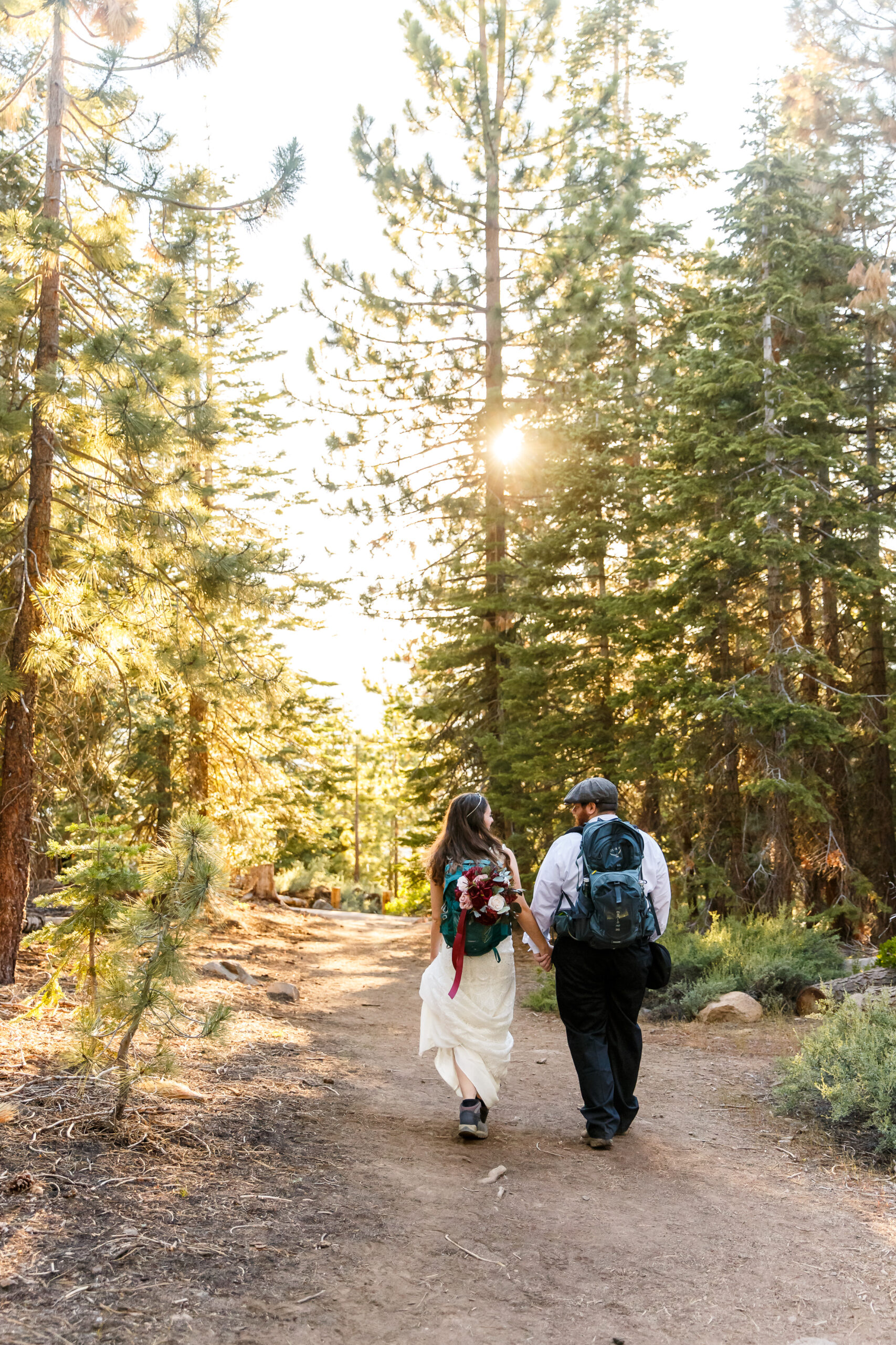 newly weds with back packing packs walking on a trail