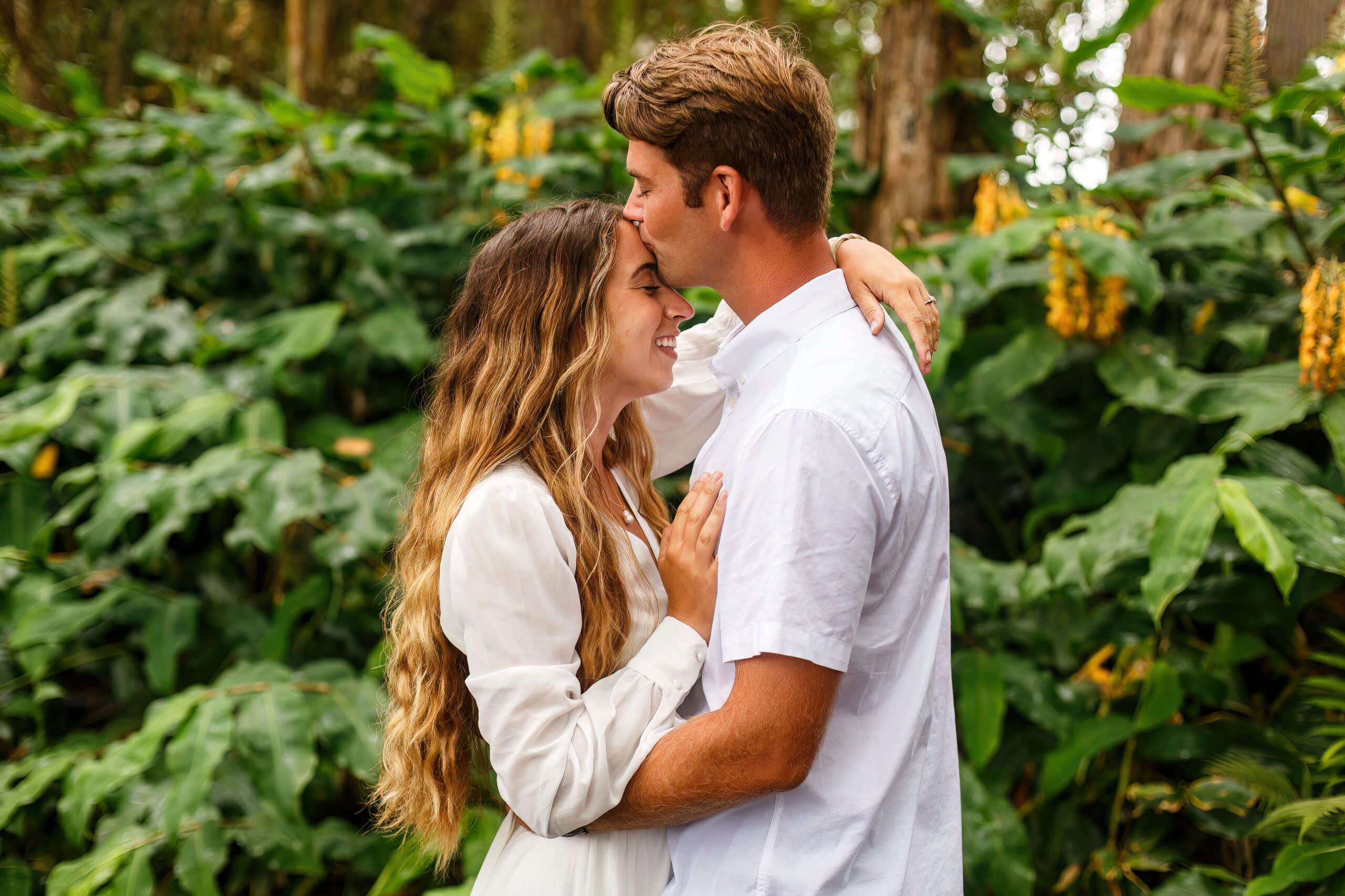 groom kissing bride on the forehead in nature