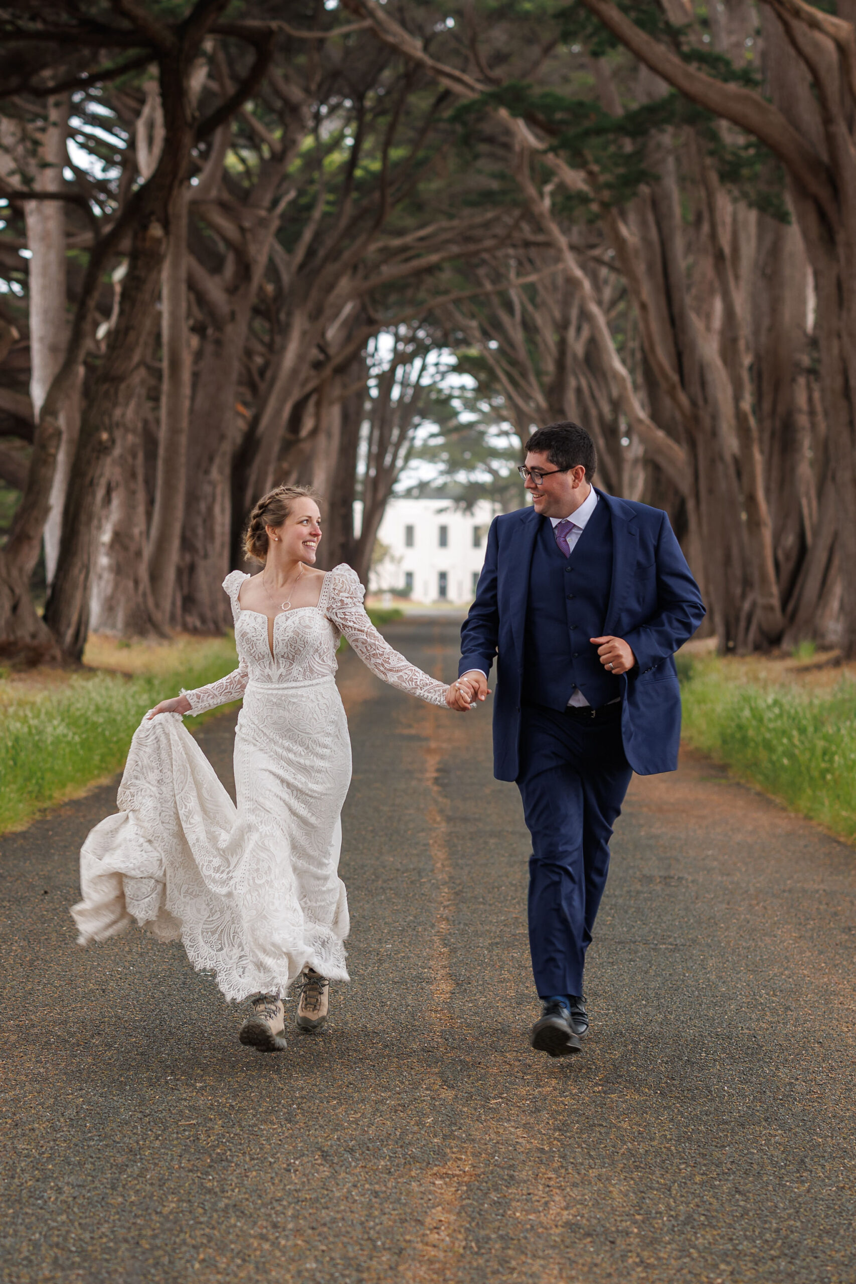 a couple running through a tunnel of trees