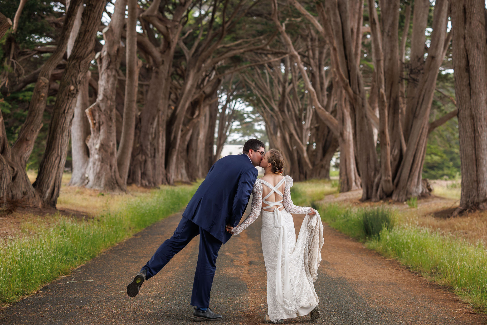 a couple walking and kissing under the trees