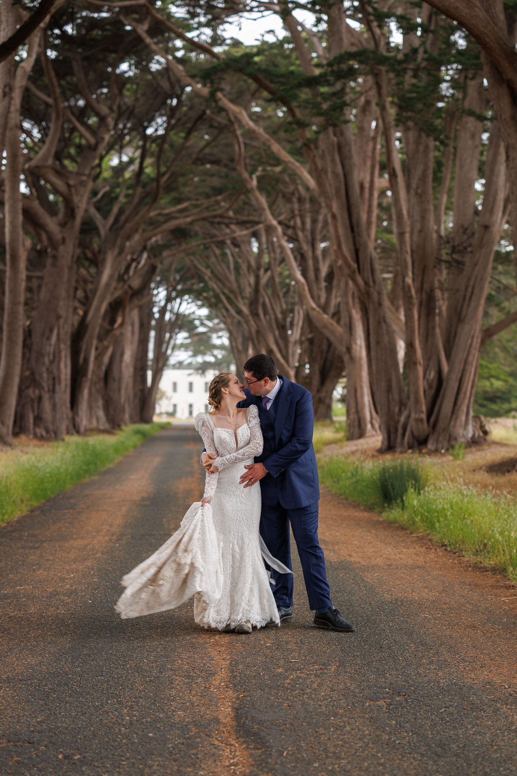 bride and groom holding each other under the canopy of trees