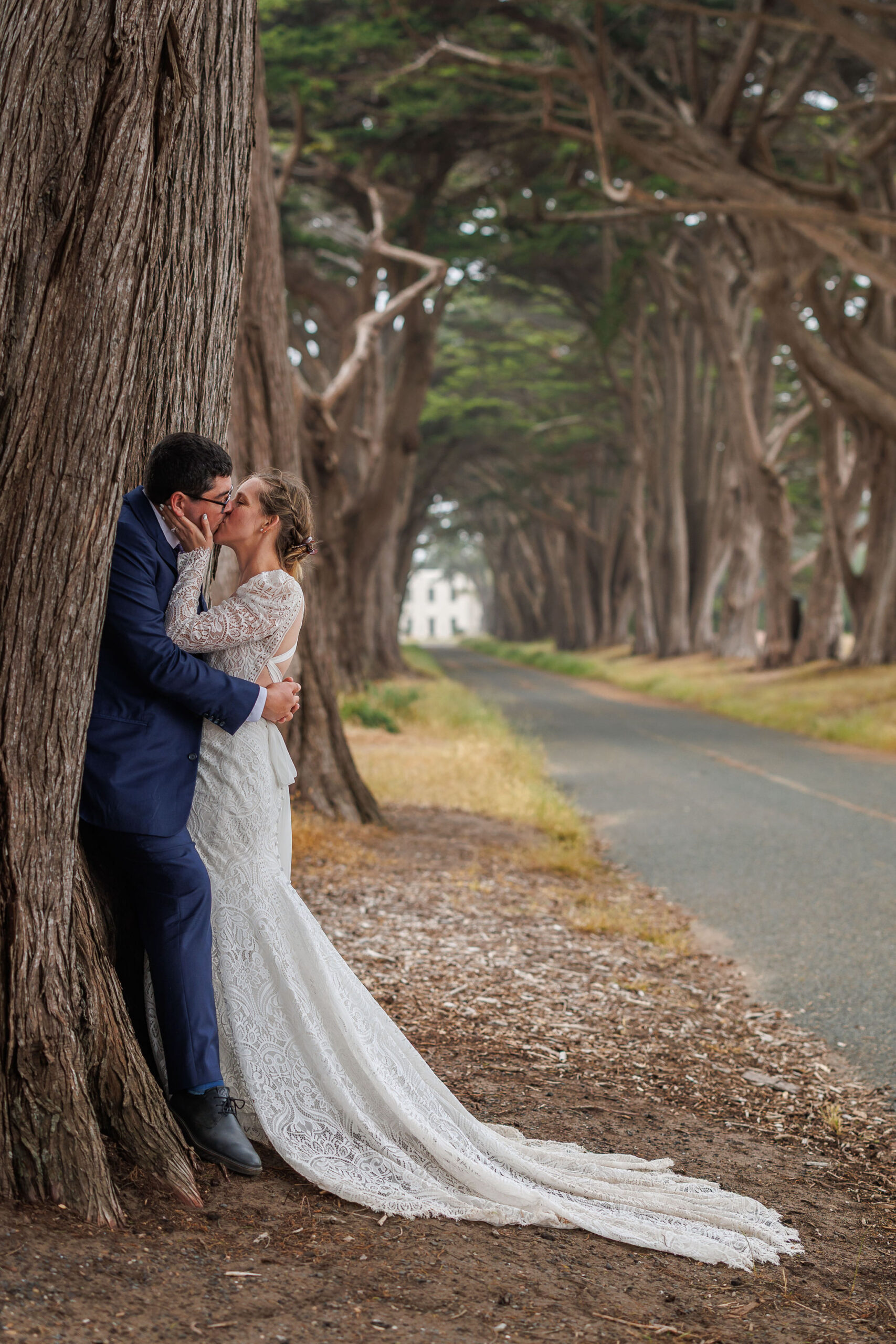 newly weds kissing against a tree