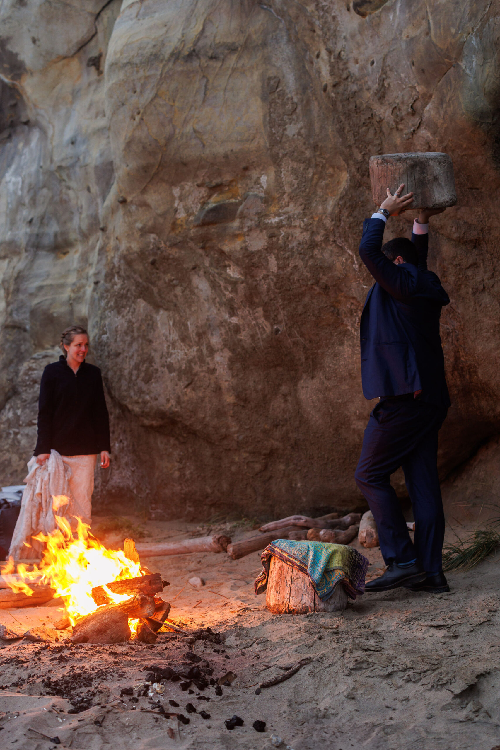 a man carrying a stump to sit on by the fire