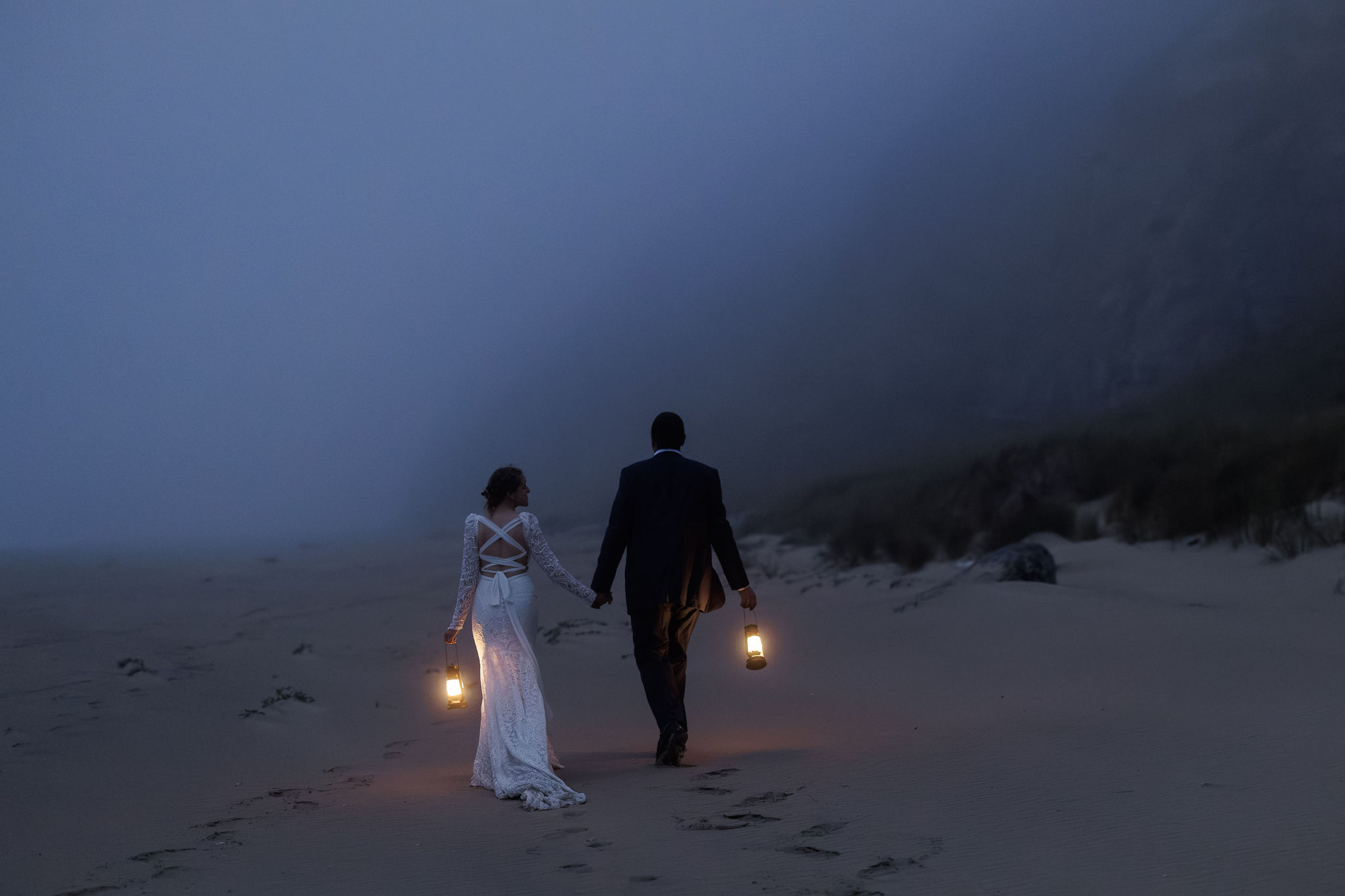 bridal couple walking in the foggy night with lanterns