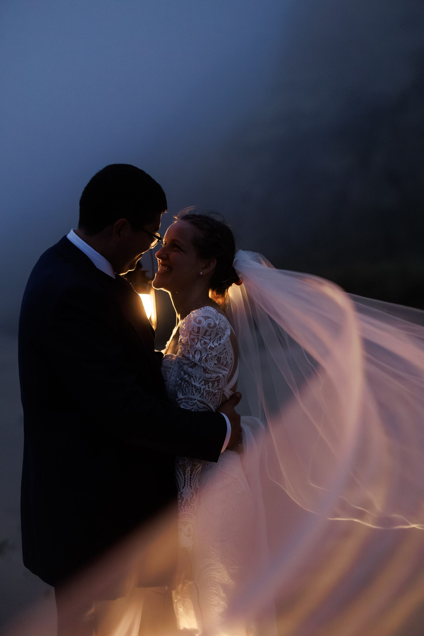 the bridal couple looking and smiling at each other on the beach at night