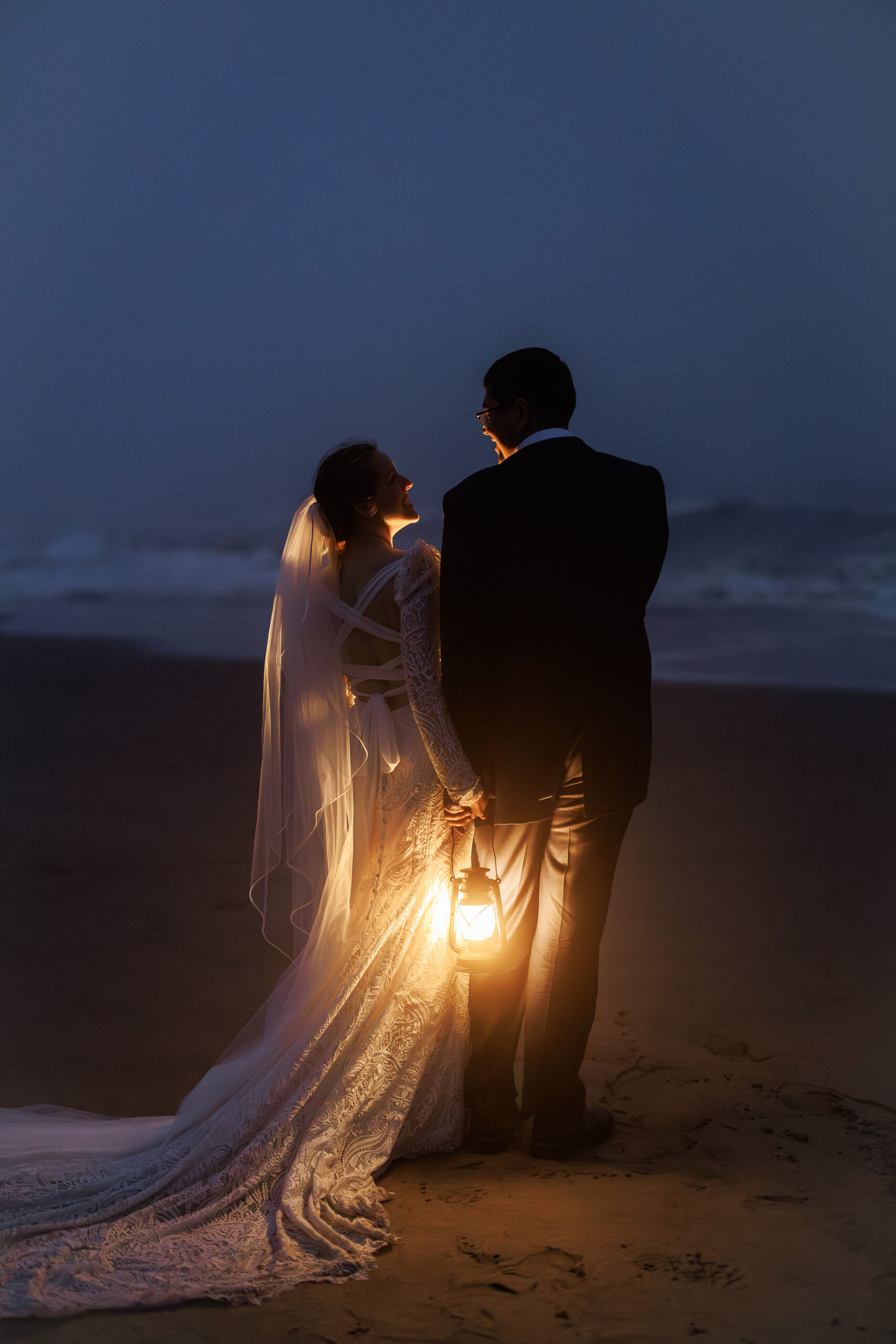 newly weds on the beach after sunset holding lanterns during their Point Reyes elopement
