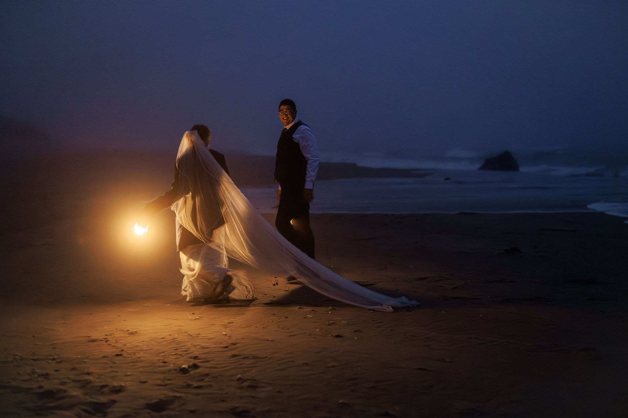 the couple walking on the beach with lanterns at night during their Point Reyes elopement day
