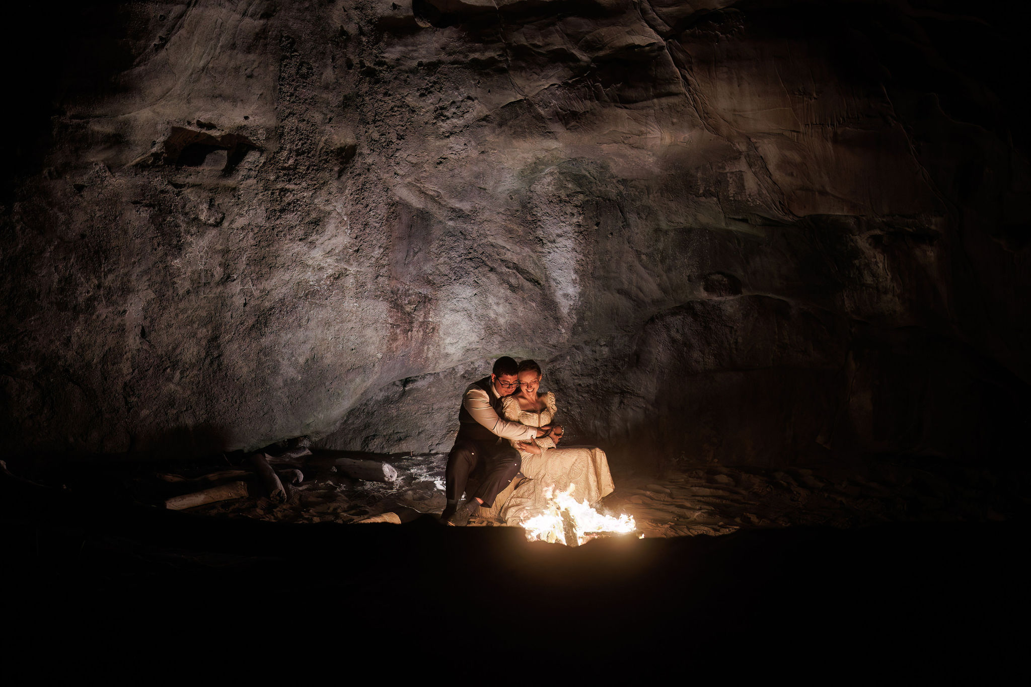 bride and groom holding each other by the fire