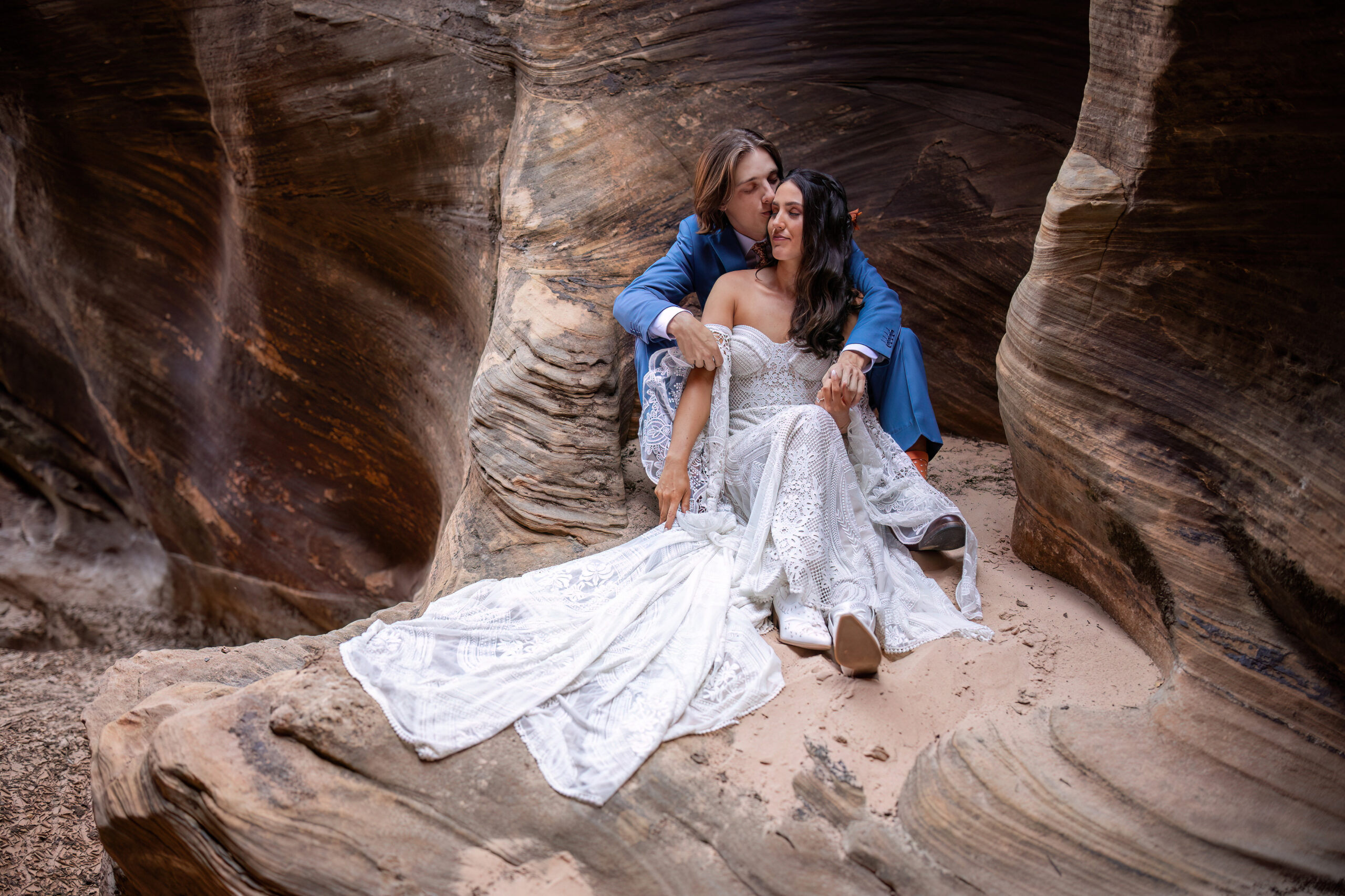a couple sitting on a rock in a slot canyon during their mountain elopement 