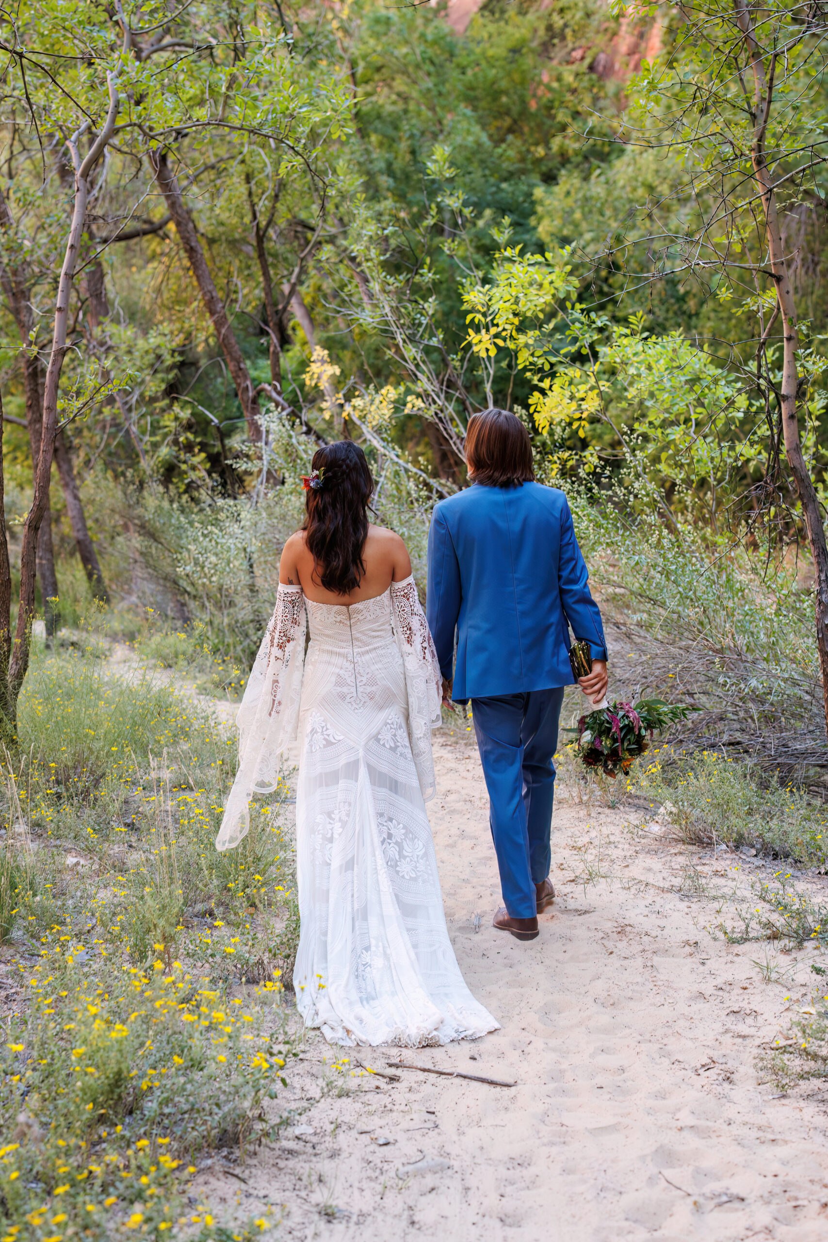 a couple walking on a tree lined path in Zion 