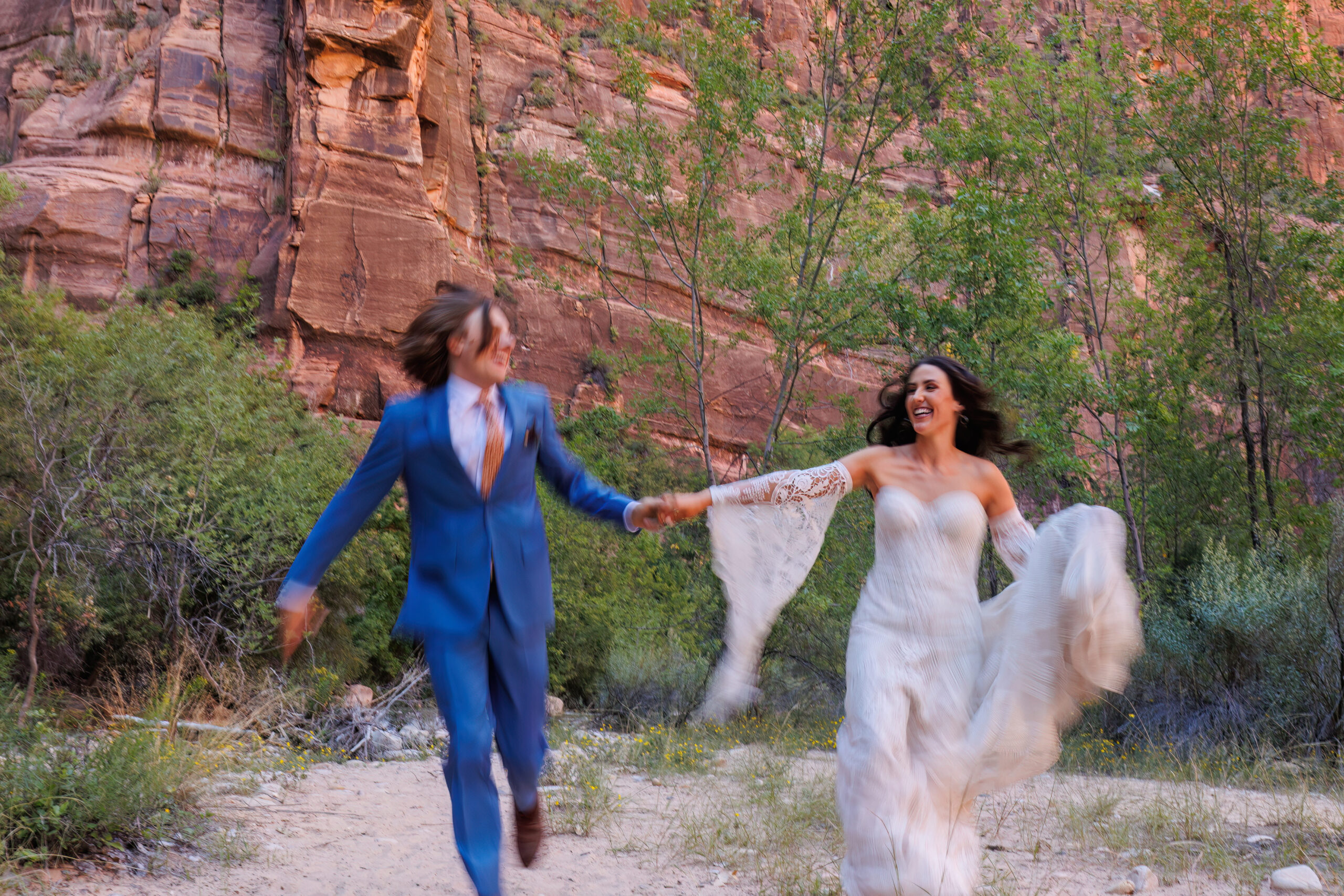 wedding couple running between the mountains in zion