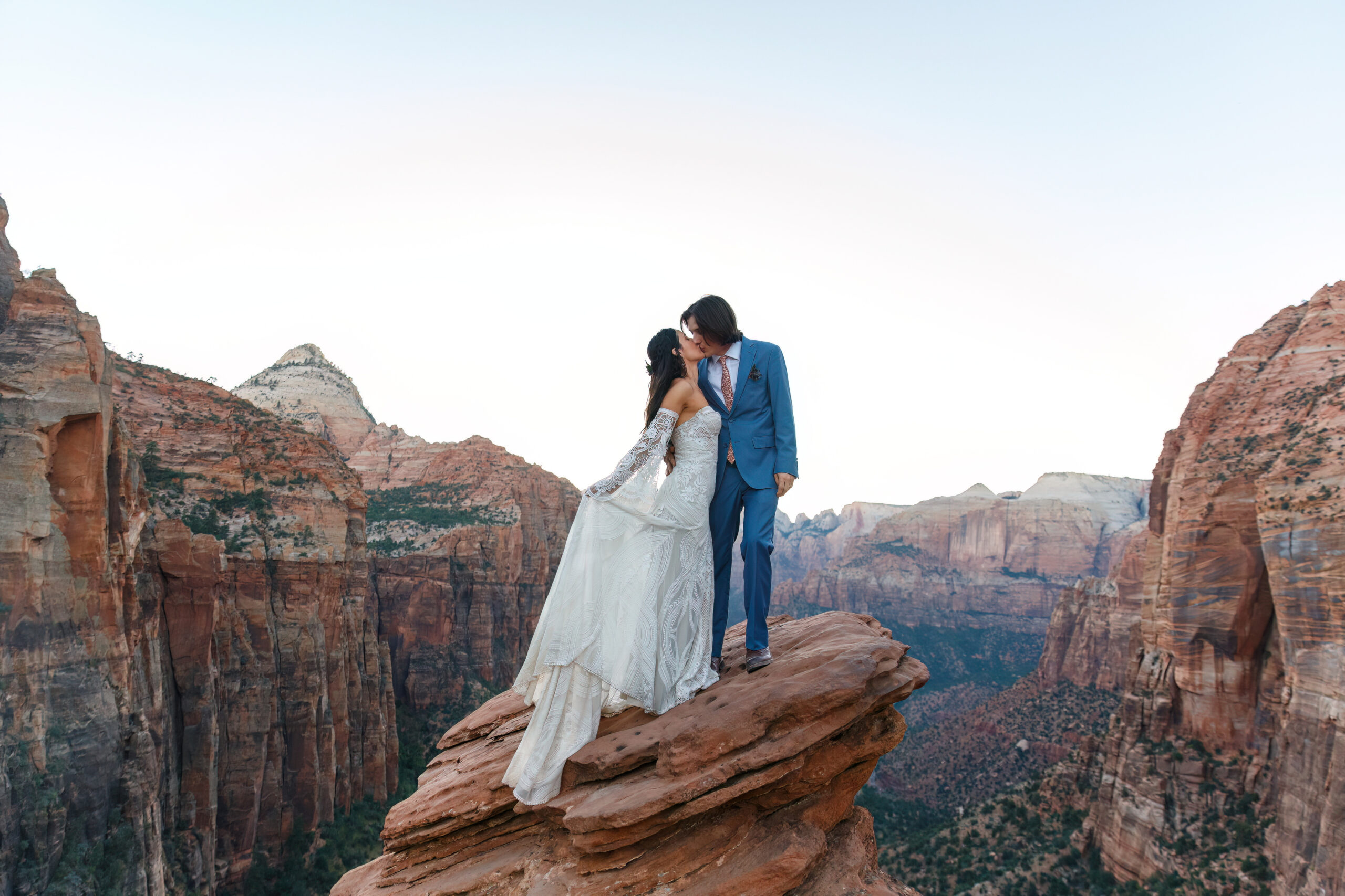newly weds kissing on a rock with an epic view at an epic zion mountain elopement location