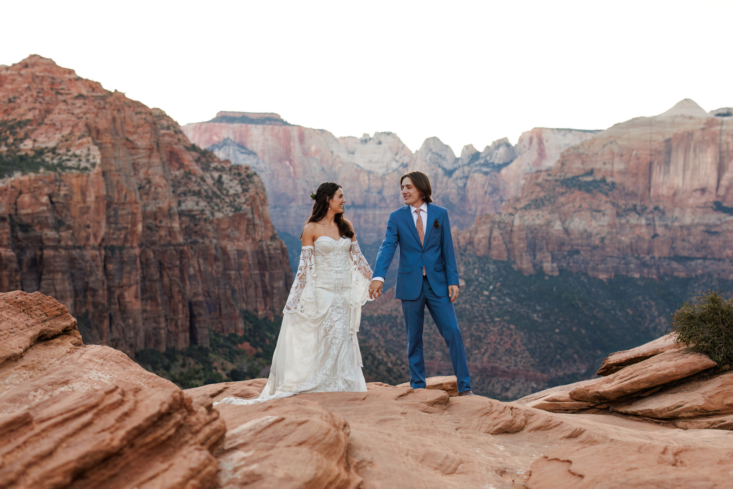 bride and groom holding hands on top of a mountain 