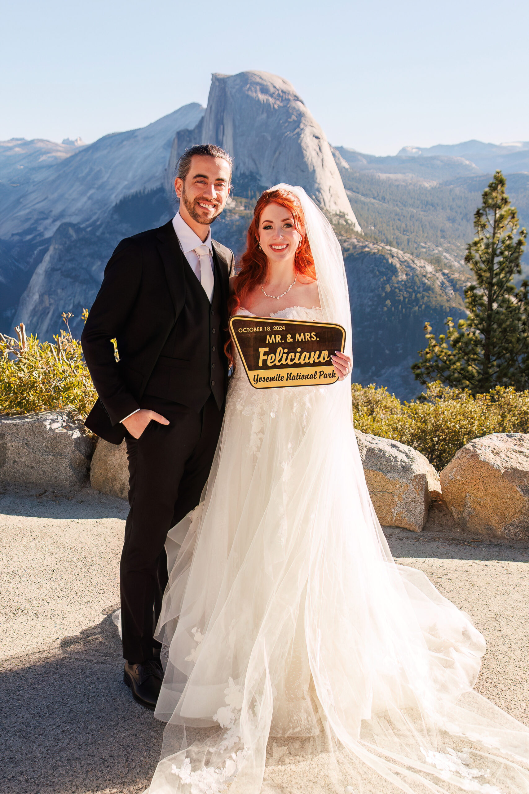 bride and groom holding up their national park sign with their married names on it 