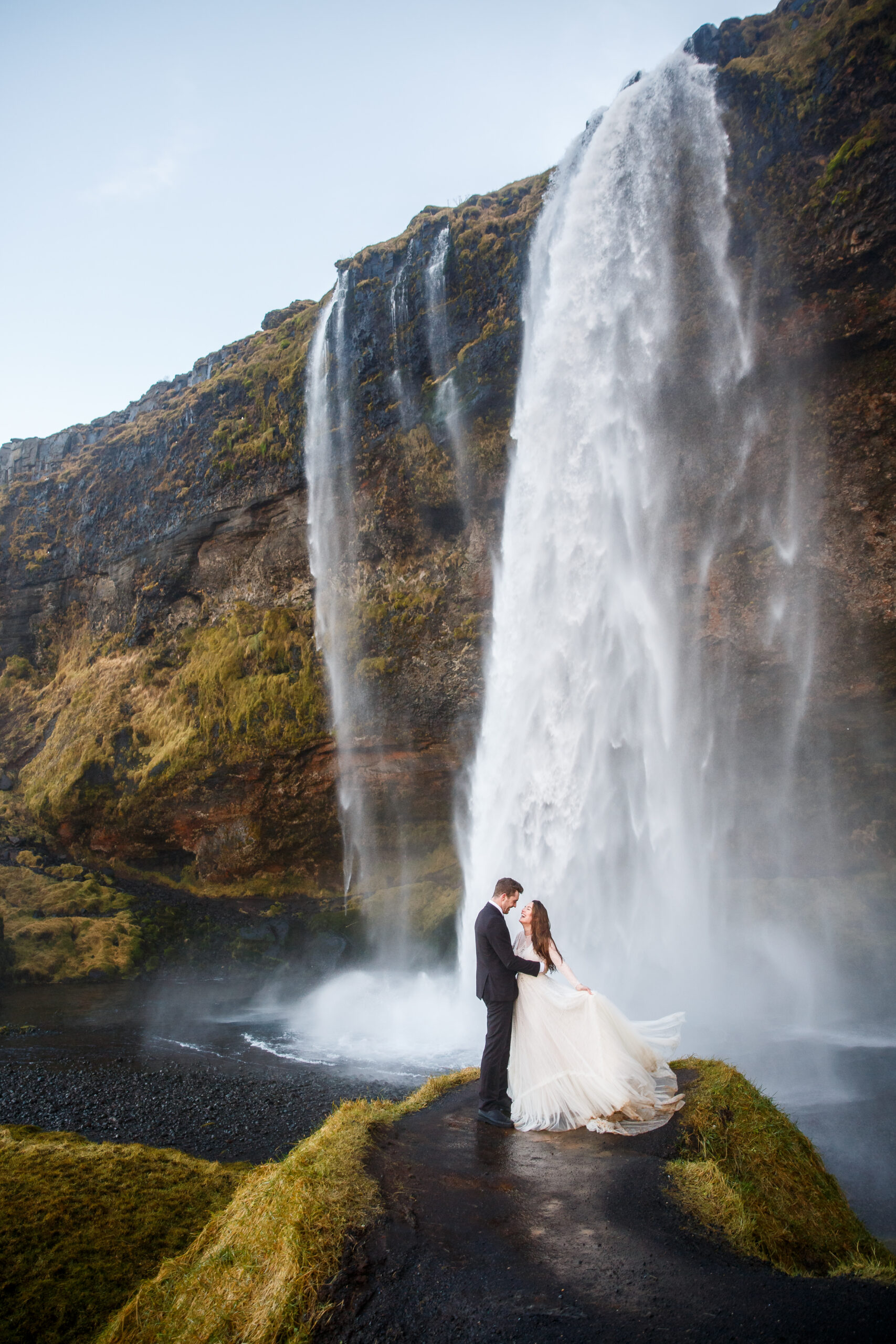 a couple standing below a waterfall in iceland for their mountain elopement 