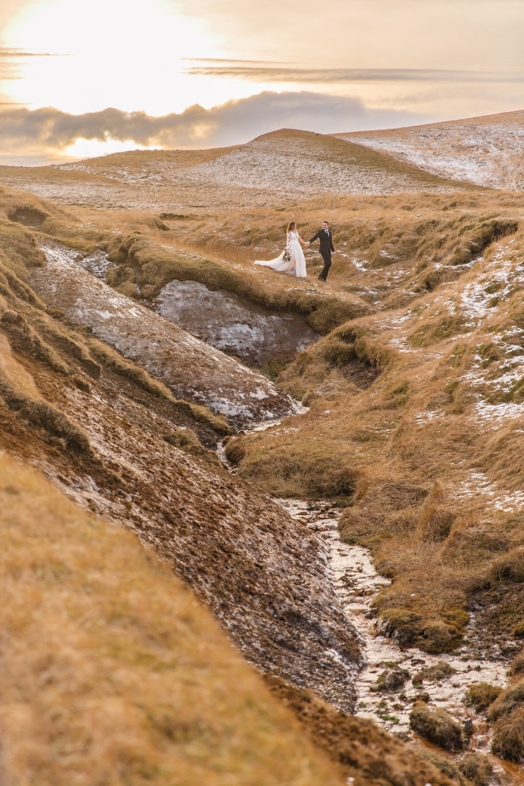 a couple walking through the rolling grass hills in Iceland